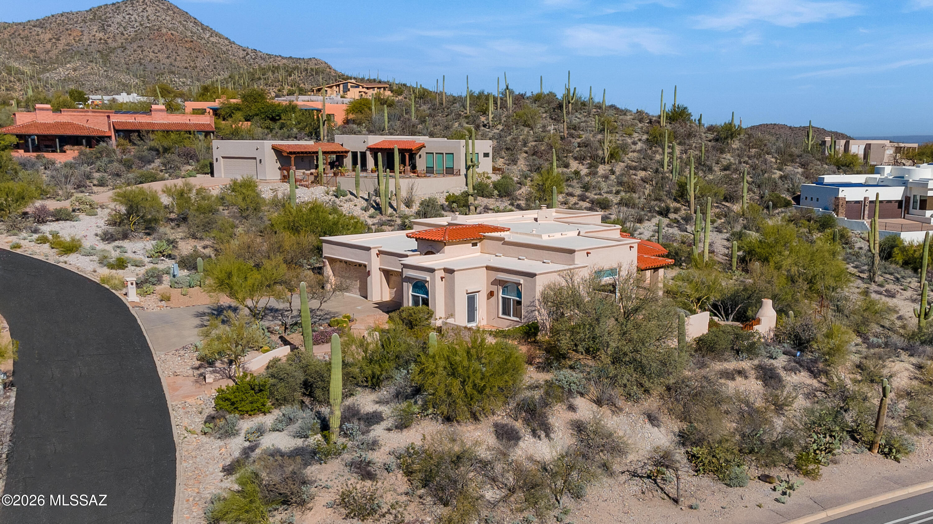 Seller will consider offers between $900,000-975,000.00. A winding concrete and flagstone walkway welcomes all to a timeless custom contemporary home within the fabulous Starr Pass community. The commanding entrance boasts a decorative wrought iron screen door, which opens to an eight foot wood front door and soaring plank and beamed ceilings in the foyer. Vaulted ceilings throughout the home accompanied by copious windows and oversized French doors provide energizing natural light. The modern chefs kitchen impresses with ample granite counter space, solid wood, dove-tailed cabinetry, stainless GE Monogram oven with travertine backdrop and solid metal pot hanger, huge walk-in pantry four burner cooktop with griddle insert, Bosch dishwasher and island with prep sink. The kitchen is open to the large great room also with vaulted coffered ceilings, can lights and dual sided fireplace. Oversized windows and doors offer beautiful views of the surrounding desert landscape, including several mature Saguaro cacti, plus mountain and city views in the distance. The large owners suite is a true retreat with a dual sided fireplace, high ceilings, can lights, ceiling fan, wonderful views through the eight foot French door and a huge walk-in closet. The primary bathroom offers a large walk-in shower with dual shower heads, a separate soaking tub and dual vanity with custom hammered copper basins. Versatile living room with terrific views could serve many purposes. Split bedroom floor plan for added privacy. Custom amenities include solid wood interior doors and Travertine stone throughout living areas.
Deep covered patio with flagstone flooring, plus separate lower sitting area with fireplace, a wonderful place to sit and watch the many visiting bird species. Gas line available at the patio for grill. Low care landscaping with drip irrigation. Over sized laundry room with utility sink. Rolling security screens, three car garage. Guest bedroom with French door access to private front patio. Dual zone HVAC units 01/2024. Just under .75 ac lot for added privacy.