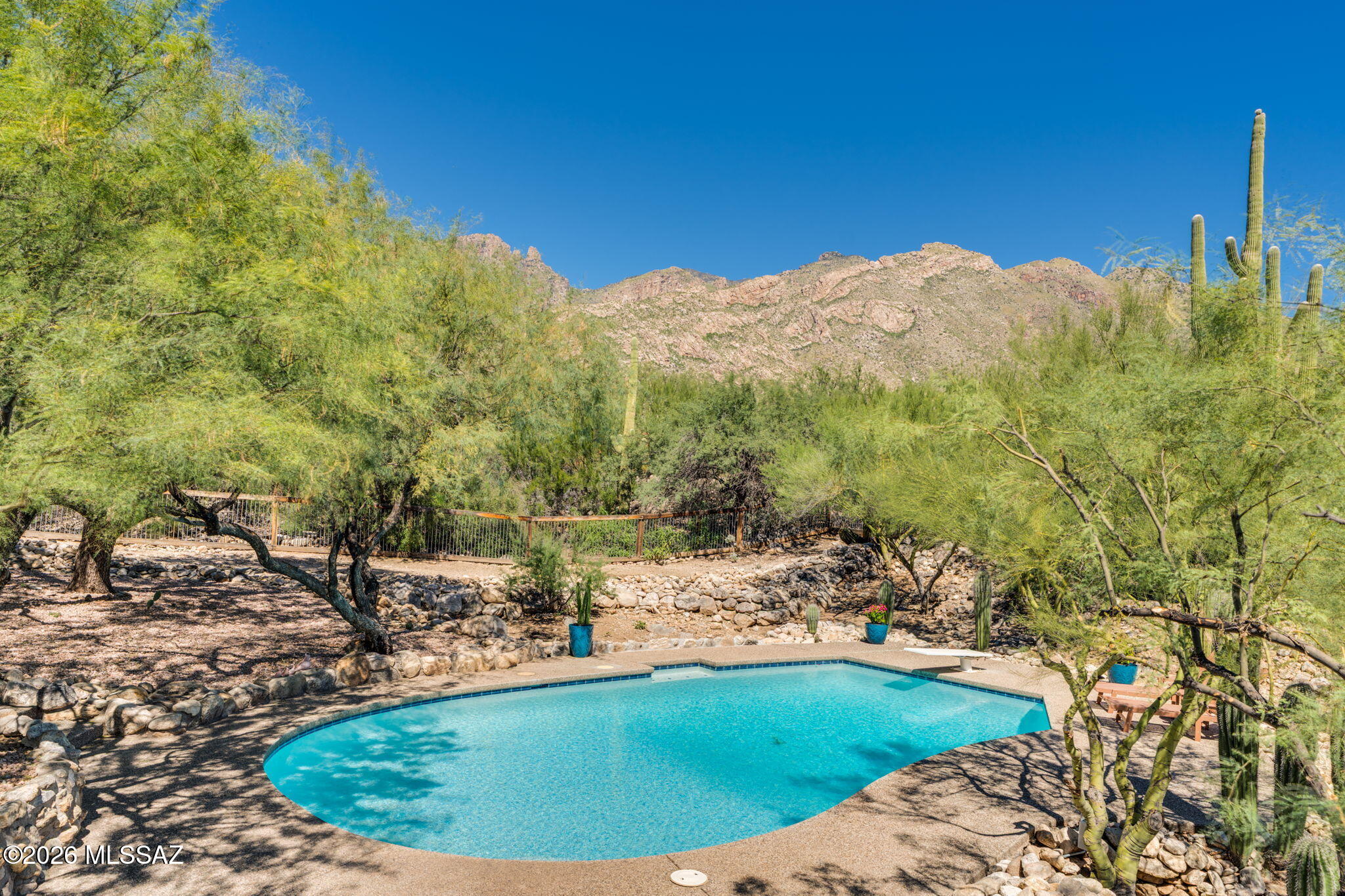 Nestled on a generous, private 0.80 acre-lot, in the Coronado Estates, this truly unique Catalina Foothills residence offers character, thoughtfully designed living space and wonderful mountain views, surrounded by a native desert setting. Inside, you'll find an open floor plan enhanced by gorgeous, exposed beams and multiple living areas; including 4 spacious bedrooms, a private library, dedicated office, 2 full baths & 2 additional half baths. Centered in the heart of the home is a true chef's kitchen complete with double ovens, cooktop, two sinks, wet bar, and an expansive center island, ideal for both entertaining and relaxed living. The primary suite features a cozy fireplace and a balcony with views. The spacious master bath is a private sanctuary and includes a walk-in closet, dual vanities, make-up station, an oversized soaking tub with picturesque views & a separate walk-in shower. Step outside to enjoy your own desert oasis with views of Finger Rock and the Catalinas from multiple sitting areas including a covered patio deck and sparkling pool. All secured behind an electric gate, this property also boasts ample guest parking, a 4+ car carport, a mechanic's dream 3-car garage with 240V power & HVAC ready set-up. Garage & pool bath could be easily converted into a separate casita. Located within the coveted Catalina Foothills School District, minutes from La Encantada, Sabino Canyon and world class golf and resorts. Don't miss your chance to tour this unique Tucson gem!