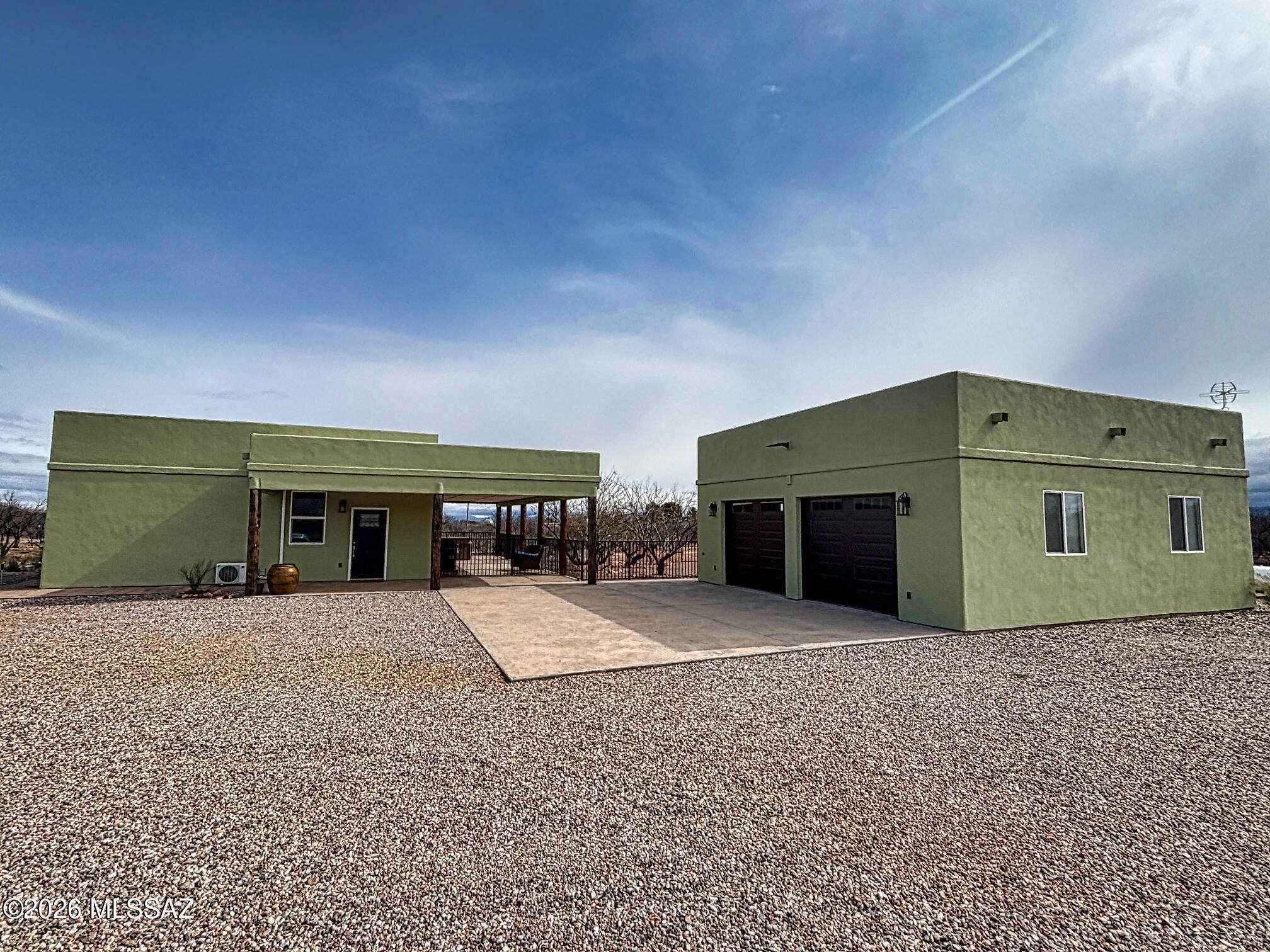 Experience the charm of Southwest living in this beautiful Territorial-style hacienda home, built just three years ago and set on 4 acres with good mountain and panoramic views. This thoughtfully designed 2-bedroom, 2-bath home features an open concept, spacious living area that open to a 50-foot wraparound covered porch, perfect for enjoying the peaceful high-desert scenery and breathtaking Arizona sunsets. Kitchen has solid wood,  custom build hickory cabinets with Quartz counter tops. Both bathrooms feature custom tiled roll-in/walk-in showers, offering both style and accessibility. Master bedroom has a large walk in closet. The property is fully fenced and gated, The home sits way back from the road and is surrounded by other homes on large parcels also. The low-maintenance yard is is accented with manicured mesquite trees and decorative gravel around the home. The oversized, extra tall garage also includes a full bathroom, mini split HVAC and separate laundry area. One half of the garage space offers excellent potential for conversion to guest quarters or extra bedroom. There are Full RV Hook ups and special touches such as the exterior faucet offers both hot and cold water. With no HOA, room to expand, and endless possibilities, this unique property combines modern construction with classic Southwest character.