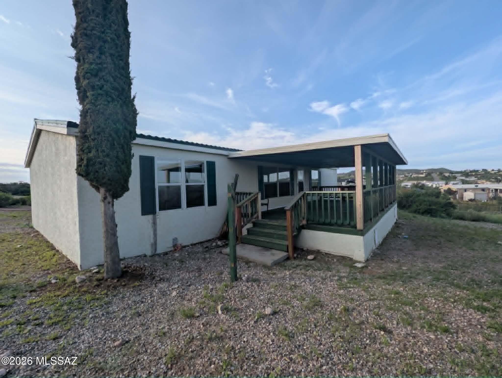 Nestled on a hill with stunning views in Historic Tombstone, this 4-bedroom, 2-bath manufactured home is currently unfinished. The exterior features a stucco finish and a durable tile-style metal roof, complemented by attractive landscaping and fencing. Covered parking is available for your car, along with a concrete pad perfect for parking a recreational vehicle.