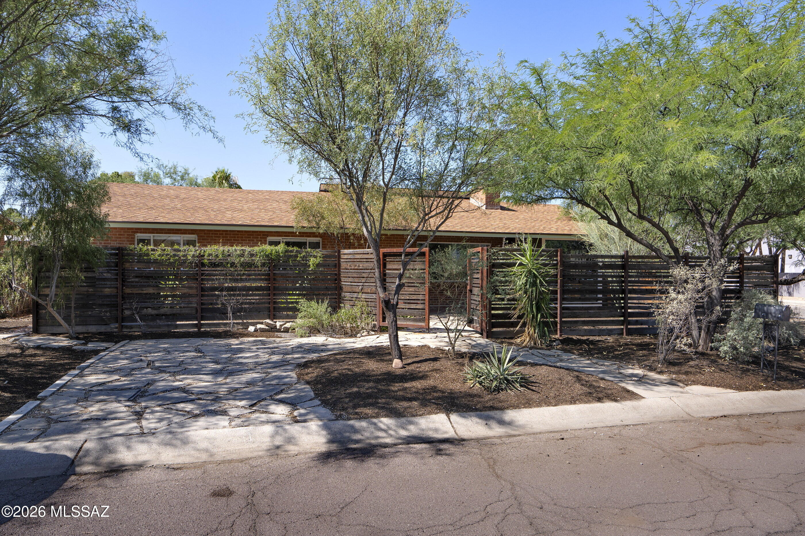 Timeless and classic 1957 brick ranch blending vintage charm with modern convenience. From the moment you arrive, the gated front courtyard provides a warm, private welcome. The home boasts an inviting large living/dining area perfect for entertaining, anchored by a beautifully updated island kitchen. Family room off the living area features a wet bar, entrance to a side patio w outdoor shower. Office and Laundry rms off the outside breezeway. Spacious Primary BR features a  private outdoor shady patio. Step outside and enjoy the tranquil large shady backyard that provides the perfect backdrop for outdoor gatherings. Car enthusiasts and hobbyists will love the 3-car garage built in 2021, offers incredible space for vehicles, workshop and storage. Solar seller owned installed in 2023.