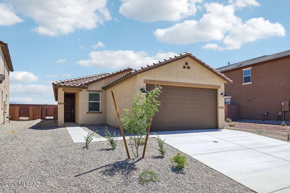 This single-story home features 9-ft. ceilings and wood-look porcelain tile flooring. The kitchen showcases 42'' white upper cabinets with crown moulding, granite countertops, an island, pantry, and Whirlpool® appliances, including a gas cooktop, smart double wall oven, dishwasher, and refrigerator. The den provides space for a home office or workout room. The primary suite boasts a connecting bath with a dual-sink vanity and walk-in shower. The laundry room is equipped with a Whirlpool® washer and electric dryer. Outside, the covered back patio faces the Santa Catalina Mountains. Price includes discount predicated on using seller's preferred lender KBHS.