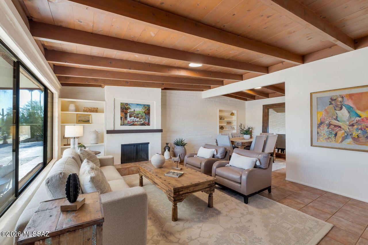 Rich in character and timeless architectural detail, this beautifully maintained 2,707 sq. ft. masonry residence blends heritage, charm, and comfort in a truly special setting. Offering 3 bedrooms, 3 baths, and a 2-car garage, the home showcases authentic mid-century design elements that add warmth and lasting value. Inside, stunning wood tongue-and-groove ceilings and exposed brick create a distinctive aesthetic, complemented by built-in bookshelves and a cozy fireplace in the inviting living room. A seamless living and dining room combination flows into a charming breakfast nook and an expansive family room featuring custom built-in cabinetry and shelving for exceptional storage and display. The kitchen is appointed with stainless steel appliances and granite countertops, providing both function and style. The spacious primary suite serves as a private retreat with custom tile work throughout the shower and dual vanities. The backyard offers a true Arizona lifestyle experience with a sparkling swimming pool, lush grassy area, vegetable garden, basketball hoop, and an oversized covered patio ideal for outdoor entertaining. A rare opportunity to own a home filled with architectural character, generous living spaces, and a setting designed for both relaxation and recreation.