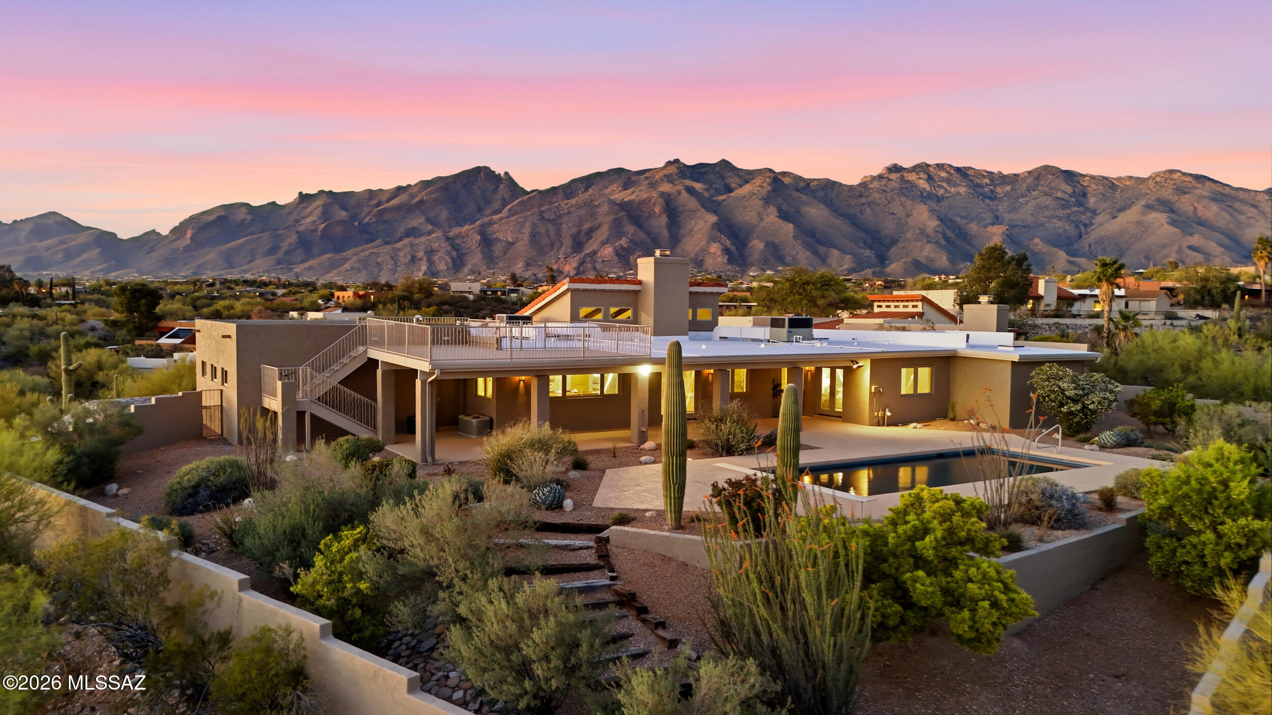 Nestled in the highly sought-after Catalina Foothills on nearly an acre, this stunning 3,126 sq ft home offers 4 bedrooms, 3 bathrooms, and breathtaking 360-degree mountain views, along with sparkling city lights and iconic A Mountain in the distance. Designed for both comfort and entertaining, the open-concept layout features distinct living spaces filled with abundant natural light and highlighted by striking wood-beamed ceilings. A double-sided gas fireplace with mesquite mantels creates a warm, inviting ambiance between the main living areas. The beautifully updated kitchen serves as the heart of the home, showcasing quartz countertops, a massive 11-foot mesquite wood island, cherry wood cabinetry, dual ovens, and a gas cooktop--perfect for gathering and hosting. The versatile floor plan includes a separate wing that can be closed off, making it ideal for guest quarters or a private primary retreat. The main primary suite features dual sinks, a jetted soaking tub, a walk-in shower with dual shower heads, a cozy sitting area, and a spacious walk-in closet. Step outside to your private backyard oasis, complete with a pool featuring an electric cover, all set on a .92-acre lot with no HOA. Additional highlights include Pella windows with between-the-glass blinds (ideal for reducing dust), extensive porcelain tile flooring, and an extended 2-car garage with a utility sink, shelving, and built-in organizers. Thoughtful upgrades throughout include two tankless water heaters for ample hot water, a pool heat pump (efficient and low maintenance), and a gas line ready for an outdoor kitchen or grill. The home is also pre-wired to convert the gas cooktop and dryer to electric if desired. From the paved, gently winding driveway to the peaceful desert surroundings, this property offers a rare combination of privacy, functionality, and unforgettable views. Foothills living at its finest.