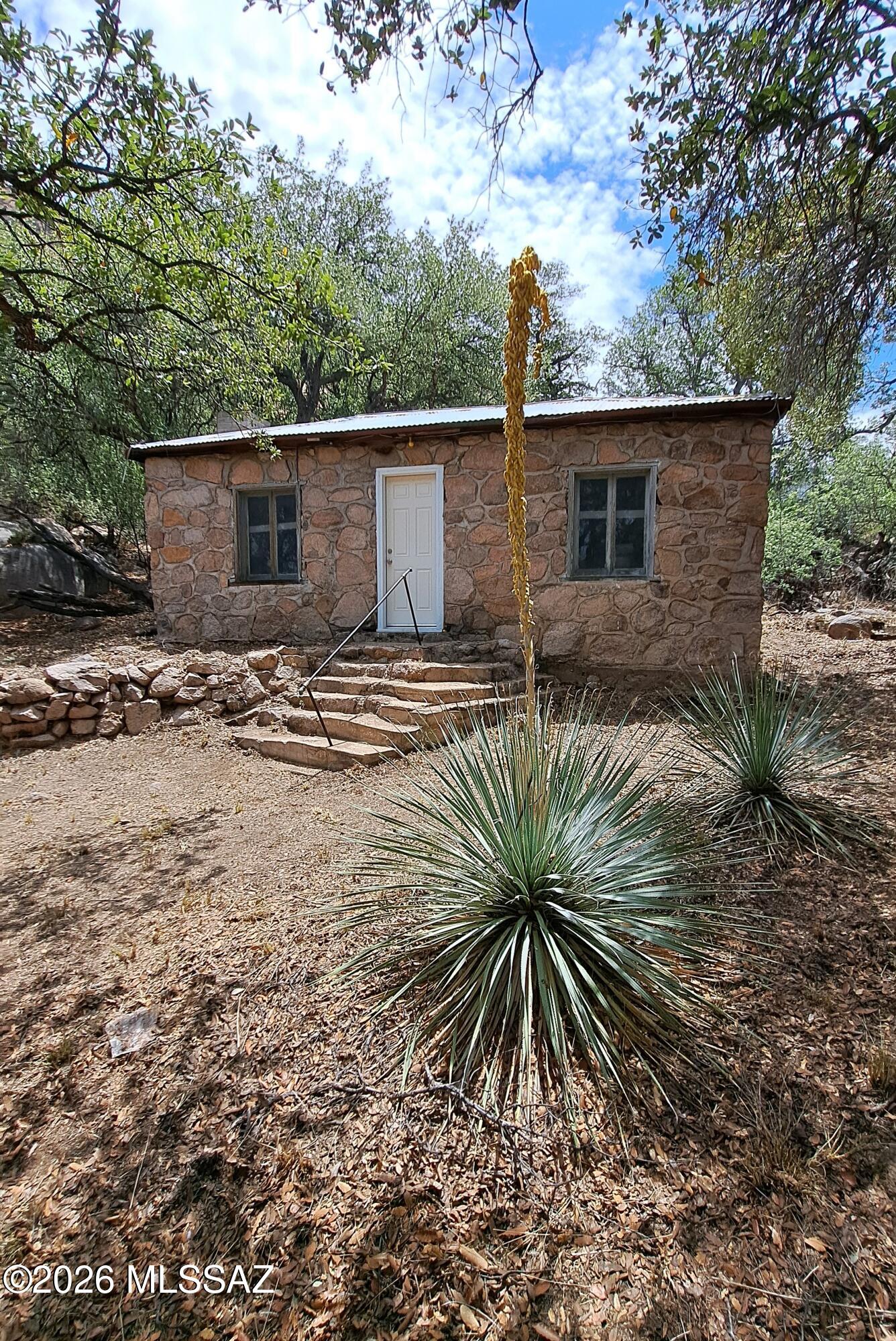 A total of 43.4 acres being sold in the coveted Banning Creek area 3 miles from Old Bisbee. There are 2 parcels-- 110-50-003 is  4.6 acre with a Stone cabin that was built by the owner's grandfather and has been in the family since.  The other 38.8 acre contiguous parcel is vacant land. This steep parcel offers stunning views as seen in the pictures. The cabin is connected to Hiway 80 by a 100 yard treelined driveway. The cabin is nestled in an oak grove overlooking Banning Creek 20 feet below.  The cabin is beyond sturdy, built with native stone, a concrete pad and a metal roof.  Inside- the ceiling material was recently removed showing wood in great shape.  Possible to remove and go with a cathedral ceiling.  The cabin is gutted essentially making a redesign that much easier. there is a wood burning cook stove, piano and a wood burning fire place. The original septic is in place but would need redress.  Water was originally brought down from a cistern across the highway in galvanized pipes, that still exist, but the link to the cistern does not. Proximity to Banning Creek would bode well for a well.  Presently there is not a power connection. APS has a pole  approx 100 feet from the cabin and the owner is in the process of investigating what the connection cost would be.  There is a large open area below the cabin along the creek that is connected by a concrete staircase with hand rail. The vacant assessor parcel number is 110-50-001c.  The tax is $764,38.813 Acres.