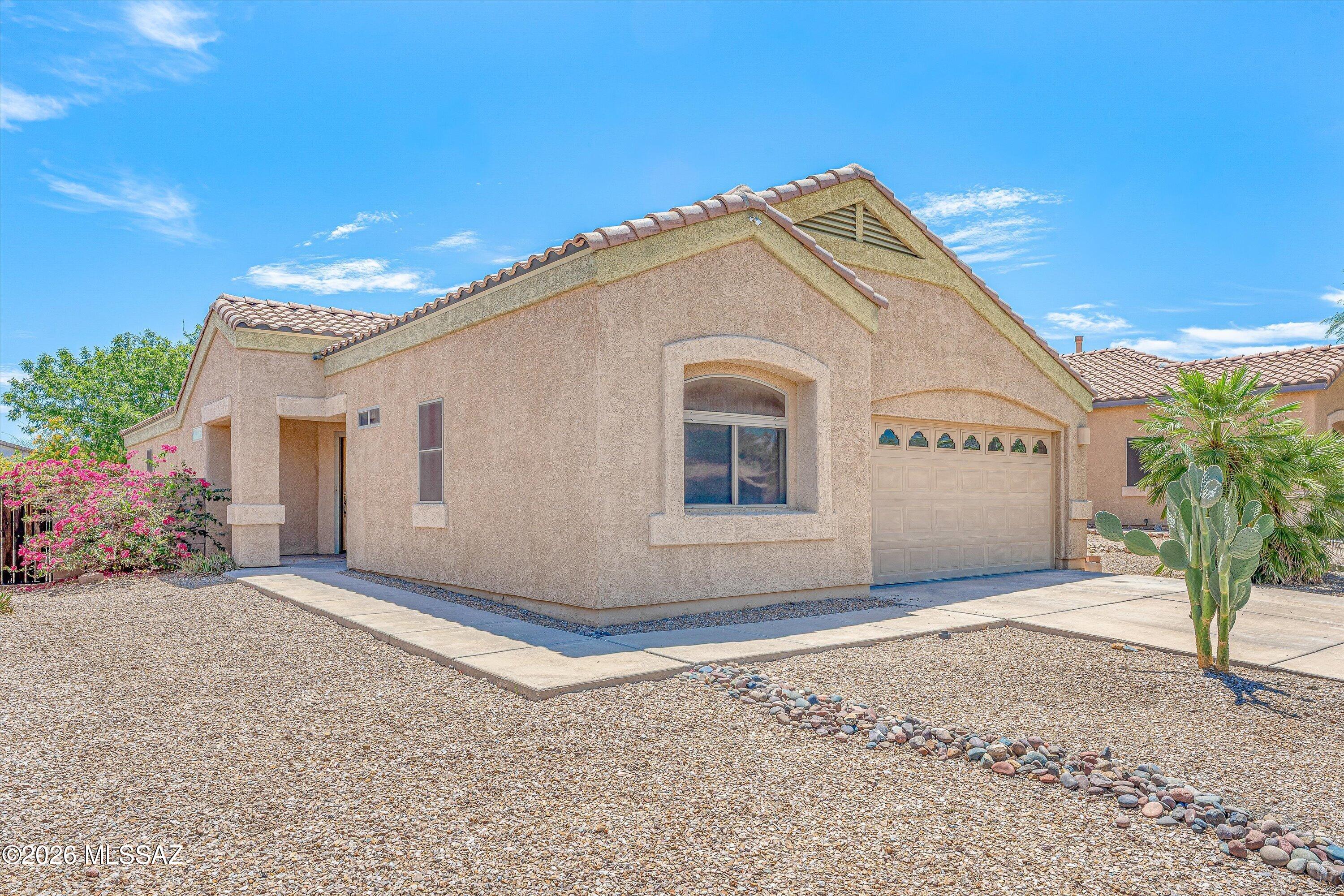 Well-maintained 3-bedroom, 2-bath home on a premium lot backing to a common area wash in Oasis Santa Rita. The great room features vaulted ceilings, surround sound, upgraded laminate flooring, and abundant natural light. The kitchen offers Corian countertops, raised-panel cabinetry, a center island with a breakfast bar, and stainless-steel appliances, and it opens seamlessly to the living and dining areas. A rare three-way split-bedroom floor plan provides exceptional privacy, with no bedroom sharing a common wall with another bedroom. Additional features include a water softener and a 2-car garage. Enjoy the covered patio, paver seating area, low-maintenance backyard, and mountain views. Located in the highly regarded Vail School District near parks and shopping.