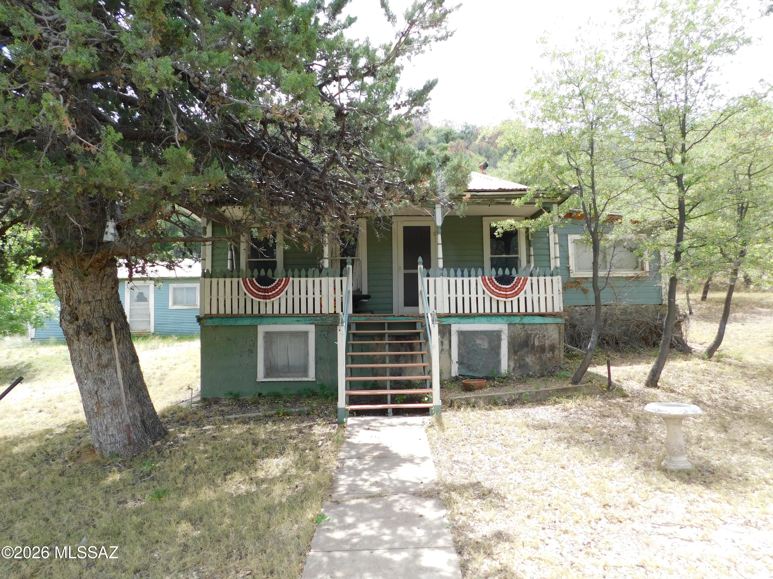 Rare Historic Homestead - First Time Ever on the Market! 7.03 Private Acres in the Heart of the Mule Mountains, Old Bisbee For over a century, this extraordinary property has been cherished by the same pioneering family. Homesteaded in 1910--just two years before Arizona became a state on Valentine's Day 1912--this authentic ranch has never been offered for sale... until now. Tucked into the breathtaking Mule Mountains on the corner of historic Old Divide Road this 7.41-acre mountainside sanctuary delivers 360-degree jaw-dropping beauty. Mature forest surrounds you as the land climbs the Bisbee Divide toward Morales Creek. Panoramic views unfold in every direction--dramatic cliffs, endless skies, and the timeless spirit of old Bisbee.The main historic.. .. .ranch home offers approximately 1,271 sq ft of comfortable living space, anchored by a remarkably large basement with cement floors and walls, windows for natural light, and convenient outside or second-floor entrances--literally built into the side of the mountain. Still a short walk or quick drive into everything Old Bisbee has to offer, including award-winning restaurants, artist studios and exceptional bands and entertainment daily.
Beyond the home, the property includes a treasure trove of original structures from Bisbee's vibrant mining era: an old kitchen and food prep/dinner hall (once serving miners' cabins), a garage, and two additional buildings ripe for creative revival--think workshops, storage, or charming guesthouses with a little TLC. Flat areas throughout provide plenty of room to build, dream, or expand. This is a true off-grid-capable retreat with a private domestic well (currently partially set up for solar, with two water tanks positioned for gravity feed). Electric and water are available on adjoining lots, and roughly half a lot sits within city limits--offering intriguing potential for annexation and access to city services (buyer to research and confirm all utilities). Five and a half of the six separate tax codes keep taxes remarkably low, with the balance in the county. The land tells rich stories: it once hosted a vintage gas station straight out of a 1940s-50s movie, and it was fully remediated by Freeport-McMoran, ensuring a clean slate. Located on the county/city line in one of Bisbee's most sought-after mountainous areas, this homestead captures the soul of Arizona's mining heritage while offering modern-day privacy and possibility. Whether you envision a peaceful full-time mountain escape, a family legacy property, an artist's or homesteader's paradise, or a unique investment/hotel/ Inn built in living history--this is a once-in-a-lifetime opportunity. Sold strictly AS IS, with no guarantees or warranties, allowing you the freedom to restore, reimagine, and make it your own. PROUDLY own bragging rights to a genuine piece of Arizona history with endless stories, memories & same gorgeous century-old views with endless potential, and endless inspiration. Properties like this simply do not come along every day. Step into a legacy carved from the mountains themselves.

SIX tax codes total acreage is 7.03 Acres:

103-60-209G is 0.04 Acres
103-60-304G is 2.14 Acres
103-60-305G is 2.03 Acres
103-60-310G is 2.30 Acres
103-60-311F is 0.45 Acres
103-60-311G is 0.45 Acres