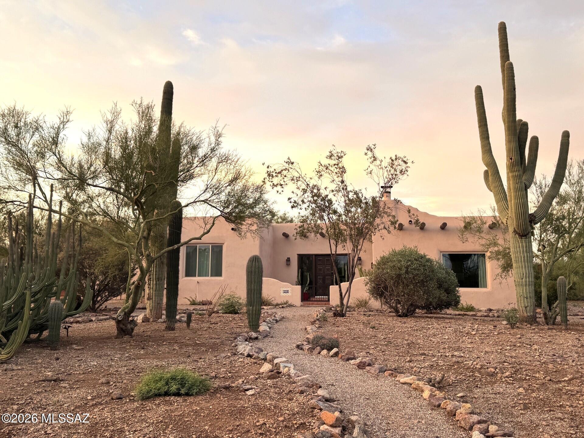 Welcome to a truly special Tucson retreat, where classic Southwest character meets the beauty and privacy of the Sonoran Desert. Set on nearly an acre with mature desert vegetation, dozens of saguaros, and sweeping mountain views, this 4-bedroom, 2-bath home offers 2,347 square feet of inviting living space filled with authentic architectural details, including adobe walls, brick and concrete floors, beamed ceilings, and a charming beehive fireplace. Inside, thoughtful updates blend seamlessly with the home's warm character, including new windows throughout and owned solar. The spacious kitchen features custom cabinetry, granite countertops, and a large center island with generous workspace, storage, and room to gather. The living room is a standout, with dramatic beamed ceilings, a cozy beehive fireplace, and views that invite you to slow down and enjoy the desert setting. Four bedrooms provide flexibility for everyday living, guests, hobbies, or a home office, while the primary bedroom frames a view of the Catalina Mountains. An enclosed, shaded patio extends the living space outdoors, offering a comfortable place to relax, entertain, and take in Arizona's desert beauty year-round. With its generous lot size, peaceful setting, energy-conscious upgrades, mountain views, and unmistakable Tucson charm, this home is a rare opportunity for buyers seeking space, privacy, and an authentic desert lifestyle--just minutes from everyday conveniences.