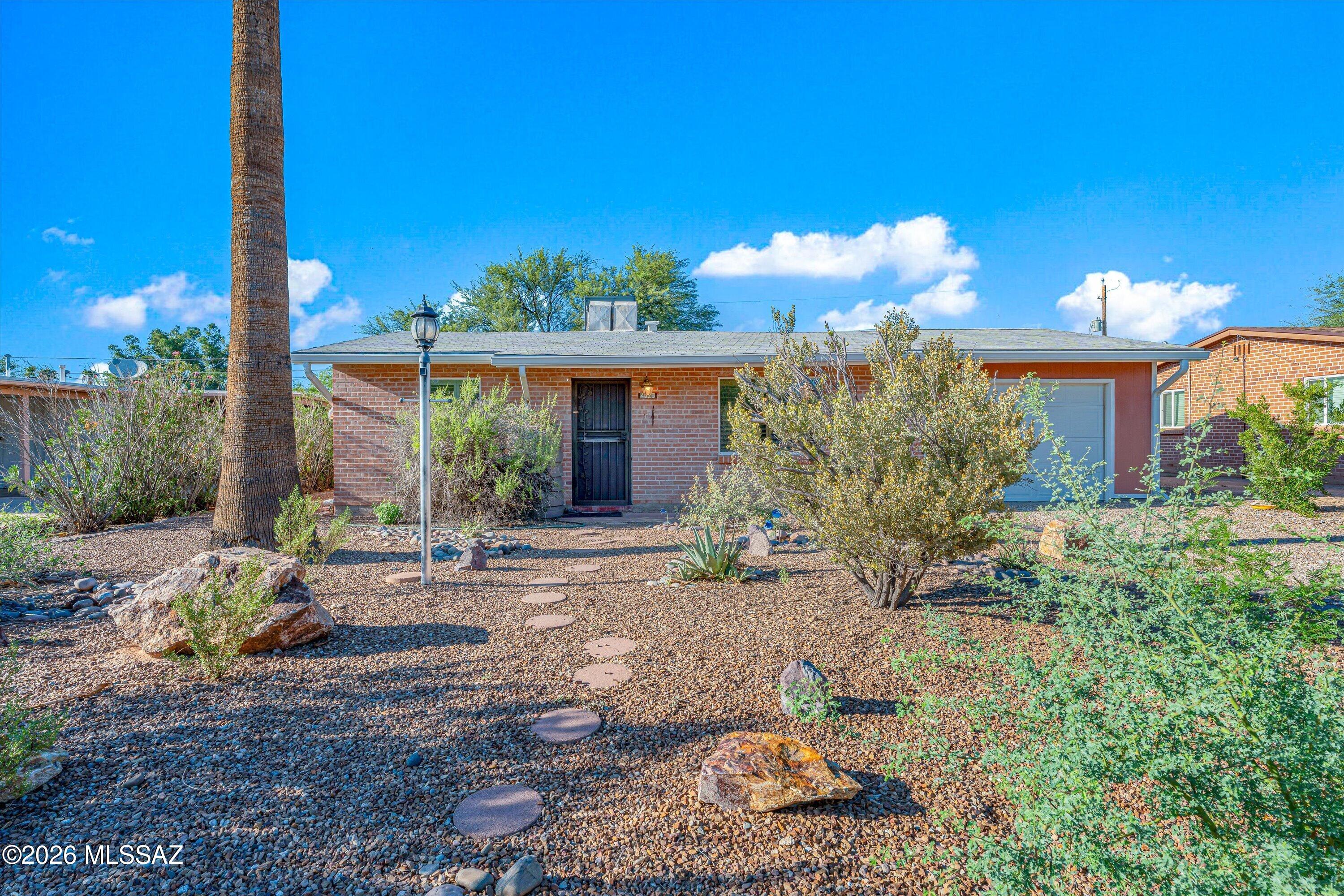 Discover the charm of this Central Tucson brick home featuring wood flooring throughout, a spacious family room with wood-burning fireplace and dining area, separate living room, and versatile den ideal for a home office, hobby room, or flex space. The laundry room offers built-in cabinetry and utility sink, while the one-car garage provides covered parking and storage. Enjoy a large lot with a peaceful, secluded backyard, covered patio, and storage shed. A rainwater harvesting tank in the front yard adds a practical, water-conscious touch. Conveniently located offering easy access to shopping, dining, parks, schools, and major roadways. A wonderful opportunity to own a piece of Tucson's classic charm with the space, privacy, and flexibility today's buyers are looking for.