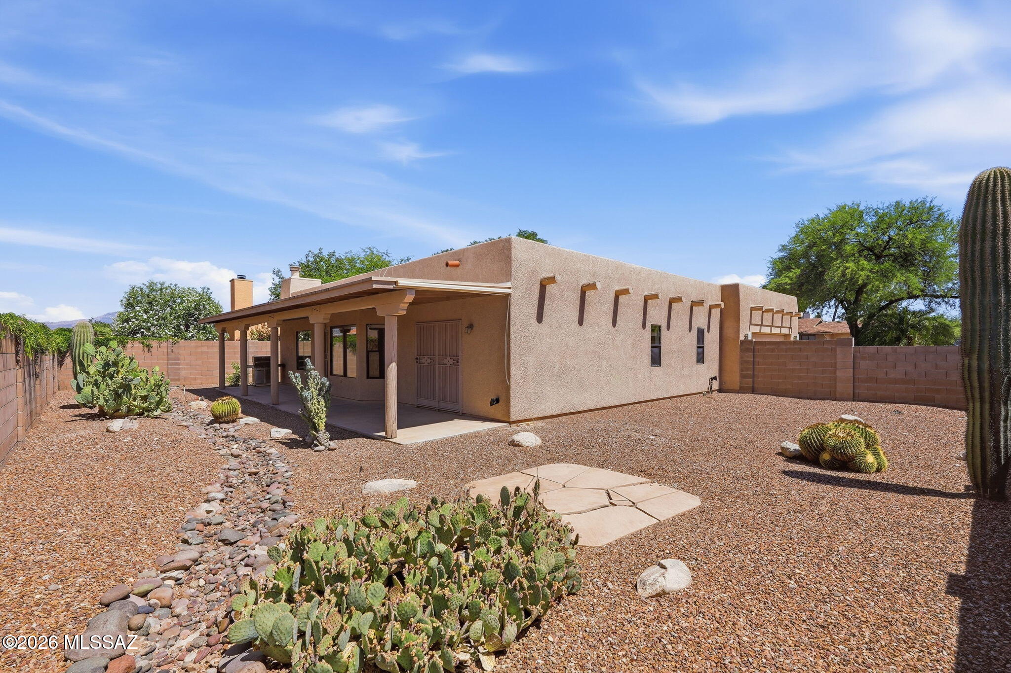 Southwest charm meets comfortable living in this beautifully maintained Santa Fe-style home situated on a spacious corner lot near the Speedway and Pantano area. The thoughtfully designed split floorplan offers 1,803 sqft with tile flooring throughout and inviting living spaces. The kitchen features a large island, Corian countertops, electric stove, & convenient pull-out cabinetry. Relax in the great room with a cozy gas fireplace and double doors opening to an extended covered patio--perfect for indoor/outdoor living. The spacious primary suite includes double vanities, a soaking tub, separate shower with rain shower head, & an oversized walk-in closet. Refrigerator, washer, and dryer convey as an added bonus. The oversized 2-car garage offers workbench, utility sink & cabinets. No HOA. Decorative security gates, professionally landscaped low-care backyard, and additional side yard complete this exceptional home.