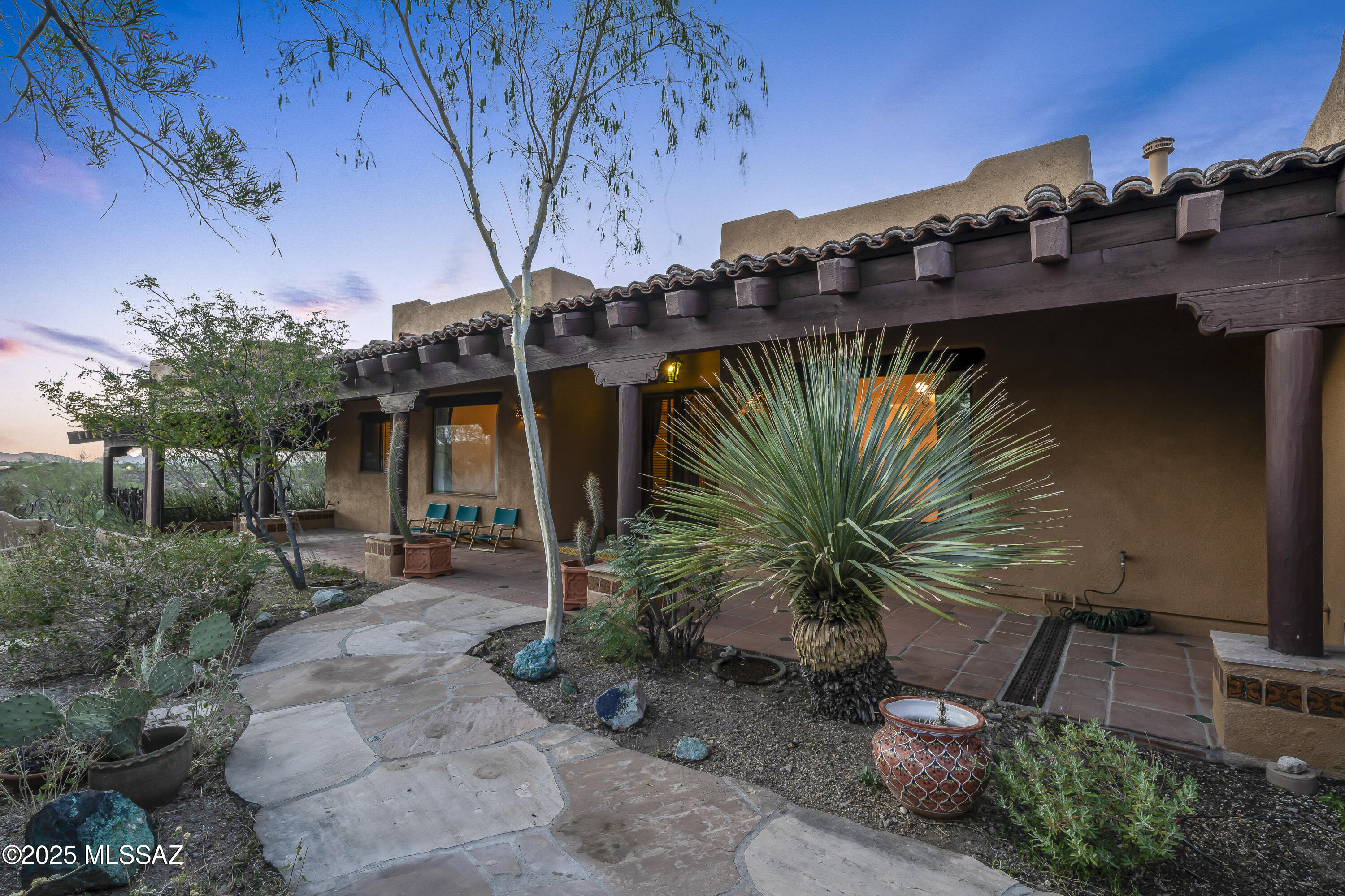 Experience the magic of the desert in this Santa Fe-style retreat on 3.3 private acres near Saguaro National Park. Surrounded by mountain views and natural beauty, this gated estate offers peace, privacy, and a true connection to the Southwest. Relax on the wrap-around porch, soak in the Pebble Tec spa, or unwind in the screened sitting room while listening to desert birds. Inside, warm wood, tile floors, and expansive windows frame breathtaking vistas. The gourmet kitchen is perfect for gathering, while the elegant primary suite with French doors, stained-glass accents, and spa-like bath creates a serene escape. With guest accommodations, office/den, and timeless Southwest charm, this home offers not just a place to live—but a lifestyle.