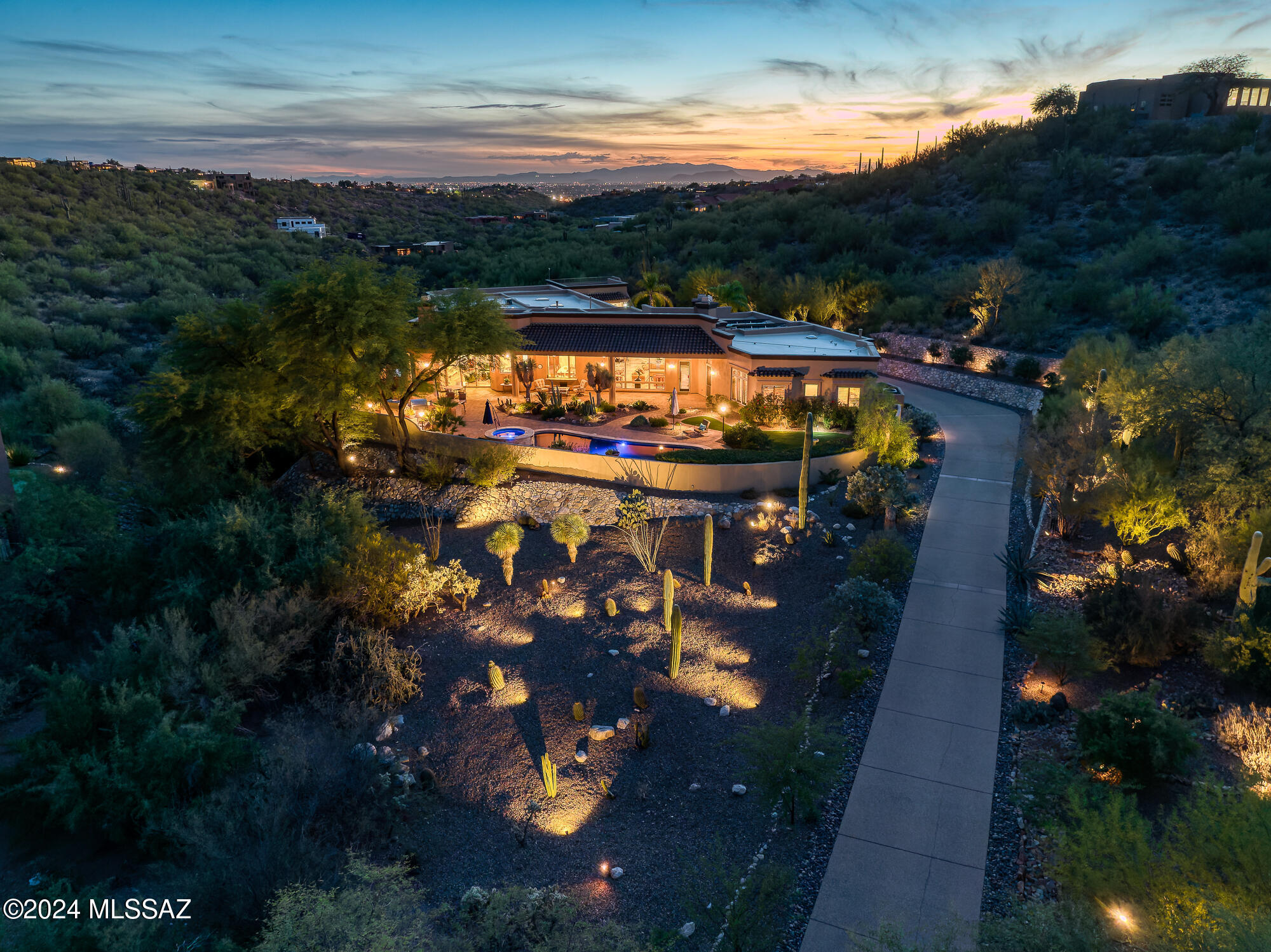 Set within the gated enclave of Rock Canyon Estates at Ventana Overlook, this remarkable single-level residence at 5043 N Marlin Canyon offers a rare combination of scale, privacy, and refined desert living. Positioned on more than 1.5 acres of manicured grounds, the home spans approximately 6,654 square feet and captures sweeping mountain views that create a constant connection to the surrounding landscape. The thoughtfully designed interior features a step-free layout with expansive living spaces that feel both grand and welcoming. Formal living and dining areas are generously proportioned, ideal for elegant entertaining, while the expansive family room, located adjacent to the kitchen, creates a comfortable and inviting hub for everyday living. A beautifully updated (continued) chef's kitchen anchors the home, appointed with premium appliances, abundant prep space, and a large walk-in chef's pantry. Just beyond, a dedicated bar area with wine refrigeration and an ice maker enhances the home's social flow and hosting capabilities. The primary suite is a true retreat, offering exceptional privacy, dual walk-in closets, and a spa-inspired bathroom designed for relaxation. A convenient secondary laundry within the primary suite adds to the ease of daily living. All secondary bedrooms are generously sized and feature ensuite baths, providing comfort and privacy for family and guests alike. A large multipurpose room, ideal as a home office, game room, or fitness space, provides flexibility to adapt to changing needs. Additional interior features include secure wine storage, an app-based home automation and audio system, and multiple fireplaces that add warmth and ambiance, including one in the outdoor living area. Outdoor spaces are designed for resort-style enjoyment. The backyard showcases a PebbleTec pool and spa surrounded by professionally curated landscaping and dramatic lighting. A fully equipped outdoor kitchen with built-in grilling stations and dual Green Egg cookers invites memorable al fresco gatherings, while the rooftop observation deck offers panoramic, 360-degree views, perfect for sunset entertaining or quiet reflection. Completing the property are modern, efficiency-minded amenities, including a fully owned solar system, a five-car garage with extensive storage, and an electric vehicle charging station. Located in the heart of the Catalina Foothills, the home enjoys close proximity, just minutes away, to acclaimed dining, shopping, golf, hiking, and luxury resorts. This exceptional estate delivers an elevated lifestyle defined by comfort, sophistication, and natural beauty, and offering that must be experienced to be fully appreciated.