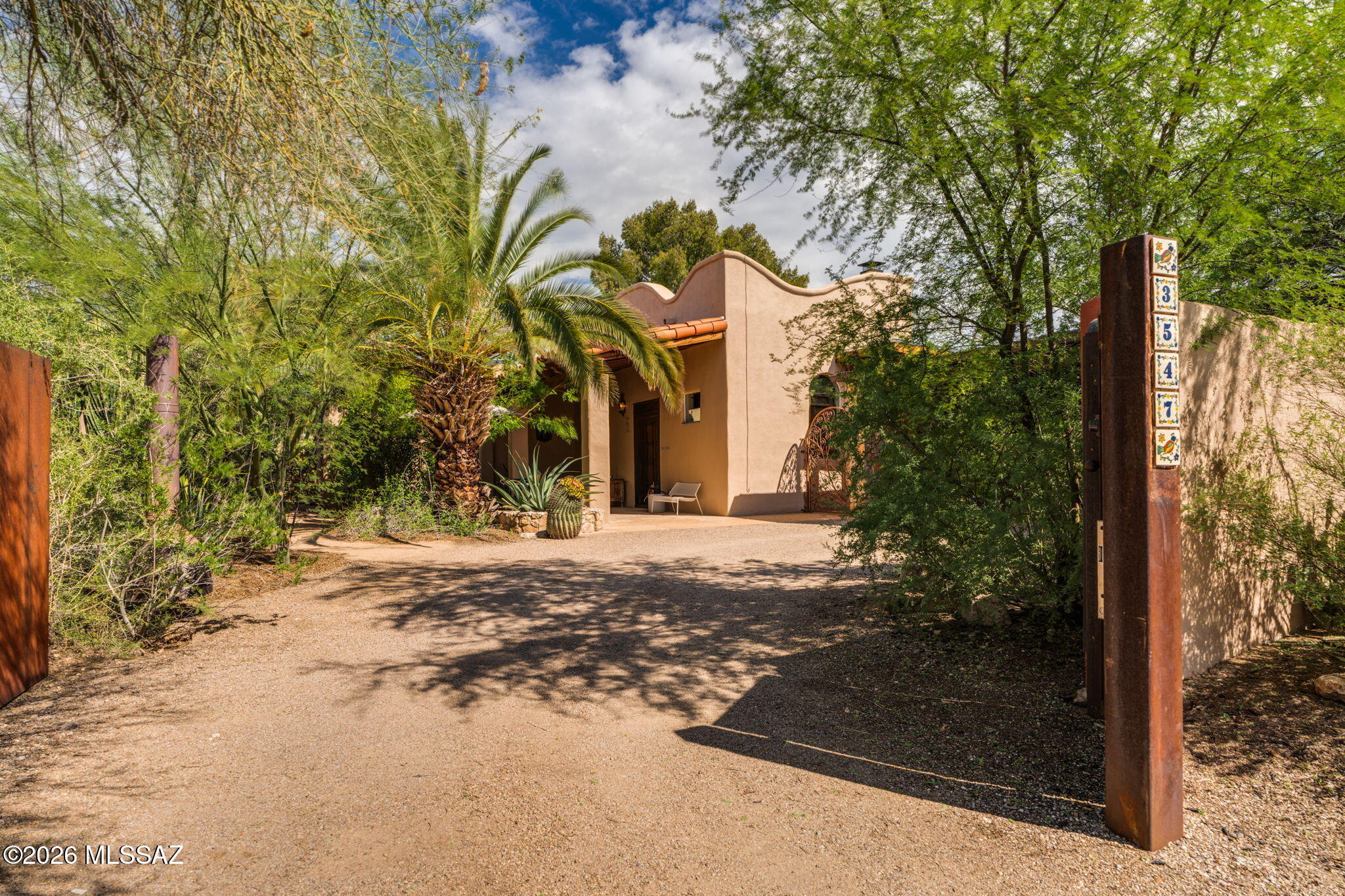 This enchanting Spanish style property, featuring a main residence and a separate guest house, blends hacienda inspired warmth with distinctive character and charm, creating a world of its own in the heart of central Tucson. Beyond tall stucco walls and a private electric gate, an inviting oasis awaits, with lush desert gardens, sheltered outdoor spaces, and a winding pathway that gently guides you through the gardens to the guest house and backyard. It's a setting that invites you to slow down and discover the quiet beauty of everyday life here. The main residence offers two bedrooms and two bathrooms, with antique Indian teakwood doors and shutters showcasing exquisite craftsmanship and intricate hand carving. Soaring ceilings with exposed wood beams, stained concrete floors, hand painted accents, and a striking beehive fireplace fill the home with warmth and artistry. A colorful kitchen and remodeled bathrooms complement its timeless charm, while French doors and carved teakwood double doors connect the great room to inviting outdoor spaces.

Nestled within the gardens, the remodeled guest house offers one bedroom, one bathroom, its own kitchen, and a bright bonus room ideal for an office or studio. A generous covered outdoor space blends naturally into the surrounding landscape, extending the sense of retreat. Together, these features create a welcoming place for guests, with potential for rental income.

Outdoors, mature palms, flowering desert plants, and fruit trees surround spaces made for quiet moments and memorable gatherings. Enjoy morning coffee as birdsong fills gardens thoughtfully nurtured to welcome wildlife. As the day gives way to evening, savor a leisurely dinner on the patio, where the gentle sounds of a nearby water feature and the soft glow of string lights create a tranquil setting. A soothing soak in the cedar hot tub beneath the night sky offers the perfect way to close the day.

With no HOA, this one of a kind property pairs the feeling of a secluded retreat with the convenience of central Tucson living. Local dining, parks, and everyday essentials are close by, along with favorites such as Whole Foods Market and The Loft Cinema.