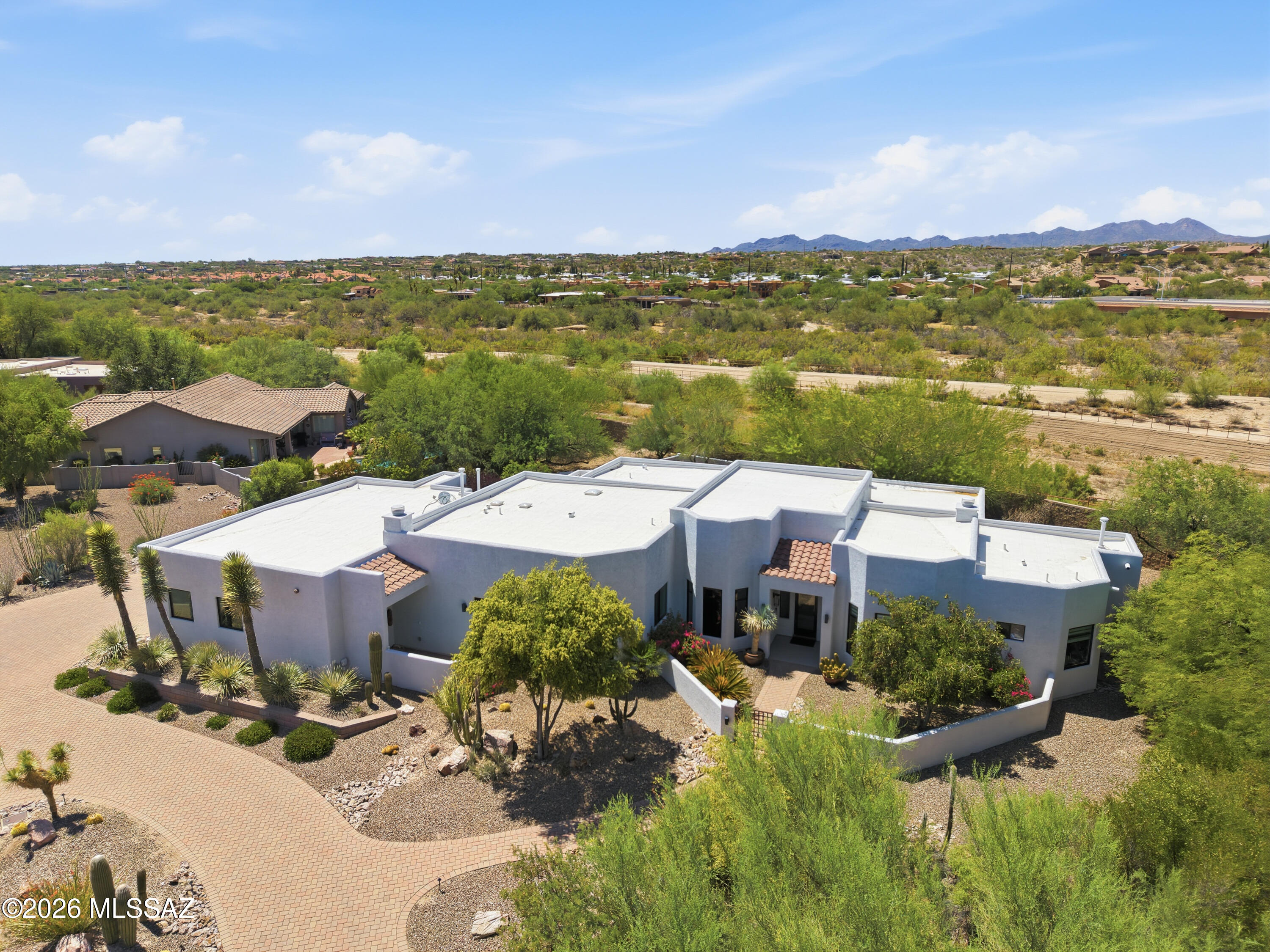 Experience a masterclass in desert luxury living with this exquisite custom-built estate, nestled directly on the prestigious Oro Valley Country Club. From the moment you arrive, a beautifully gated front courtyard welcomes you, hinting at the privacy, elegance, and premium finishes that lie beyond the threshold of this 4BD/3BA (3,095sqft) contemporary ranch. Designed around a thoughtful, light-filled split floor plan, the home opens into an elegant formal living and dining area crafted for high-end entertaining. At the heart of the residence is a gourmet kitchen that serves as a true culinary haven. It features custom alder cabinetry, thick quartz countertops, a massive central island, an oversized walk-in pantry, and a butler's pantry equipped with a beverage cooler. Premium appliances elevate the space, anchored by a Forno 8-burner gas cooktop, double ovens, and a built-in Monogram refrigerator. The kitchen transitions into a comfortable great room featuring a cozy fireplace, perfect for relaxed daily living. The master suite is a private sanctuary, complete with its own gas fireplace, a scenic bay window, and a spa-like bathroom boasting a soaking tub, a walk-in shower, and a custom-built walk-in closet system. Two additional guest bedrooms share a Jack-and-Jill bath, while another bedroom could serve as a home office. Almost every window in the home serves as a picture frame for stunning, unobstructed views of the Catalina Mountains. Outdoor living is nothing short of spectacular. An expansive covered patio overlooks a professionally landscaped, 0.55-acre oasis. Complete with an oversized 3-car garage featuring spacious storage rooms, and a Tesla EV charger, this property positions you perfectly to enjoy premier country club amenities, local pickleball courts, and immediate access to the famous 131-mile multi-use Tucson Loop bike path, as well as Oro Valley's premier shopping and restaurants.