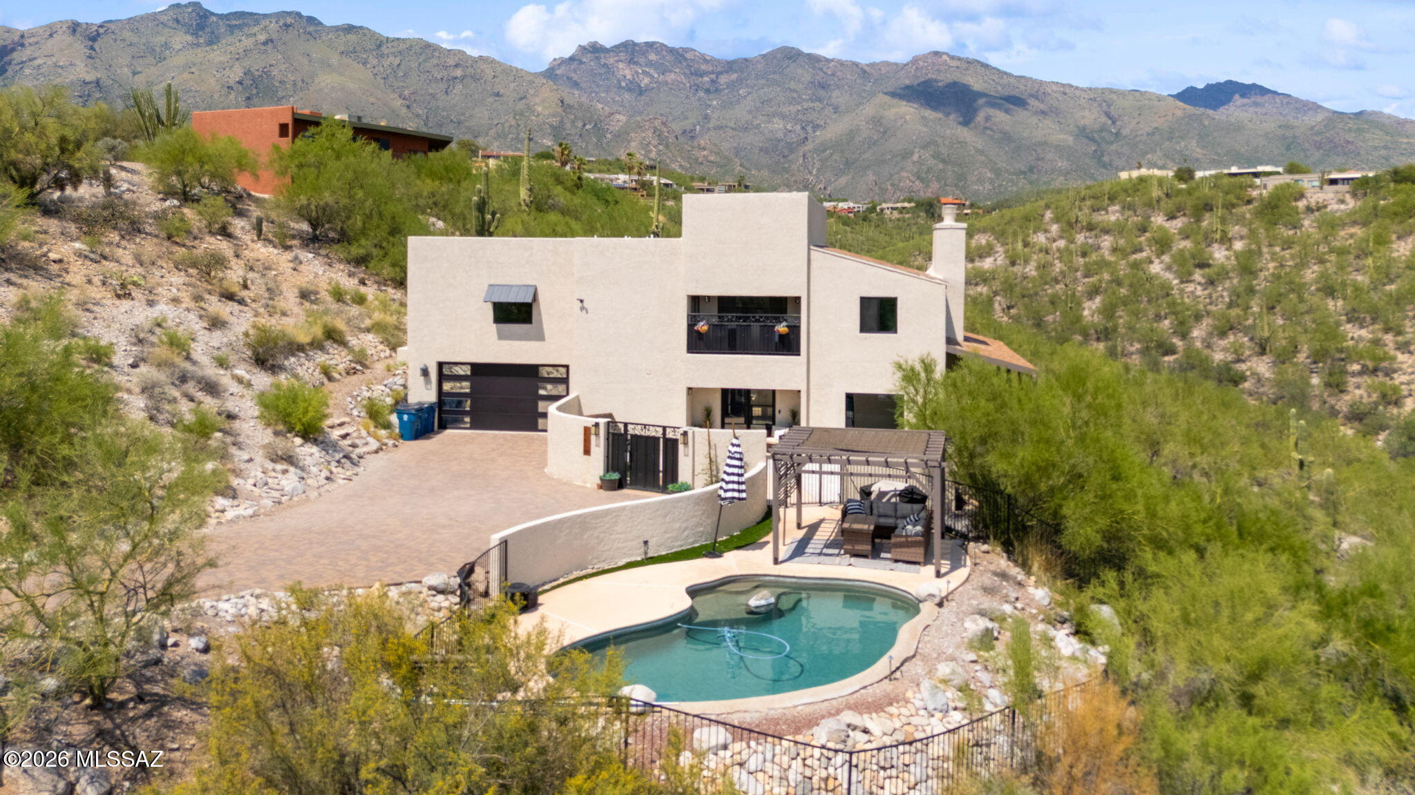 Fantastic Foothills home set on 1.77 acres w/ panoramic mountain + city views, privacy & beautifully designed indoor-outdoor living. Enter through the custom iron gate to be welcomed by the redesigned courtyard. The pool & pergola create an inviting space for entertaining. The large primary suite features a generous walk-in closet, updated solid-wood Shaker cabinetry w/ soft-close construction, quartz countertops, & designer lighting. Additional recent improvements include upgraded lighting, flooring, interior + exterior paint, custom iron staircase, HVAC systems + mini-splits for additional temperature control, garage door & epoxy flooring. Energy-efficient upgrades include multiple Low-E Milgard windows & new sliding glass doors. The 300 sq. ft. first-floor bonus room (not included in... the assessor's square footage) has loads of possibilities as a home office, exercise room, guest space, or creative studio.
This large parcel features exceptional views & a peaceful setting. It blends privacy, comfort & convenience in Tucson's highly sought-after Foothills neighborhoods.  The HOA includes patrol services to provide added peace of mind. Restaurants, shopping & everyday amenities are just minutes away. Located in the Catalina Foothills School District.