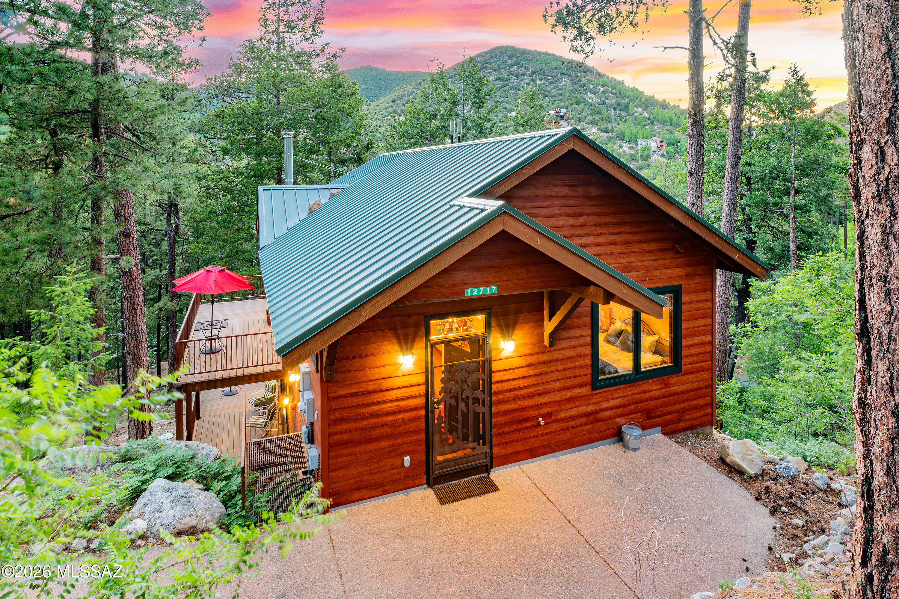 Never before offered, this custom 1,249 sq. ft. Mount Lemmon retreat presents a rare opportunity to own a thoughtfully designed mountain cabin nestled among towering Douglas firs, Ponderosa pines, and dramatic granite outcroppings. Built in 2009 by respected builder Dennis Cozzetti, this owner-designed home is ideally situated on an expansive double lot (approx. 0.32 acres) to maximize privacy, forest views, and outdoor living.
Enjoy sweeping treetop vistas from spacious Trex decks, while the lower portion of the property features terraced landscaping, lush fern-covered slopes, and a large level gathering area ideal for entertaining, outdoor games, or simply relaxing in the mountain setting. Additional features include a paved driveway, underground propane tank, county-maintained year-round road access, and a nearby fire hydrant.
Inside, warm Australian Cypress flooring flows throughout, beginning in a welcoming and functional entryway, through the spacious main and lower floor living areas.  The bright great room, anchored by a Jotul wood stove and framed by Sierra Pacific glass doors and windows, showcases the surrounding forest. The inviting kitchen offers custom cabinetry and pull-out pantry storage. The main level includes a bedroom and full bath, while the lower level features a separately keyed guest suite/studio with a bedroom, kitchenette, full bath, laundry area, and private deck access, ideal for guests, extended family, or flexible living arrangements.
Designed for year-round comfort, the home includes dual-zone forced-air heating, on-demand hot water, a three-stage engineered septic system, fiber-cement siding, and a durable metal roof. An unfinished basement-level workshop and storage area provides additional space for tools, outdoor gear, and hobbies.
Offered fully furnished and equipped, this turnkey retreat includes furnishings, décor, kitchenware, linens, internet equipment, and outdoor entertaining amenities for immediate enjoyment.
Walkable to Summerhaven and nearby hiking trails, this exceptional property combines thoughtful design, quality construction, and an unforgettable mountain setting. See documents for the complete feature and upgrade list.