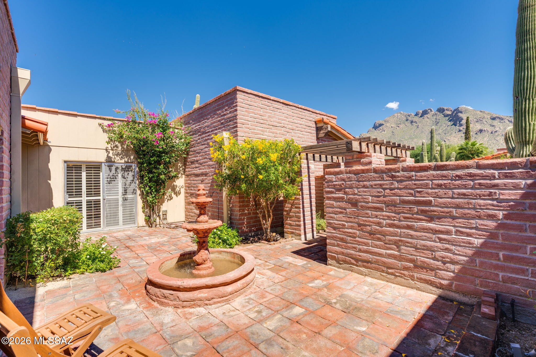 Rare opportunity for one of the few larger units in Casitas Del Oro Norte. Peeks of Pusch Ridge welcome you home to your inviting courtyard with rustic adobe pinto pavers, flowering shrubs & a relaxing fountain. Handcarved wooden door brings you in to the spacious 2 Bedroom + Den floorplan featuring a wood burning beehive fireplace & premium Tradewinds Cedar Shutters throughout. Soak up the sunsets from the extended covered patio with prep sink & built-in cabinets for entertaining. Kitchen is full of storage with a wall of cabinets, under cabinet lights & solar tube skylights. Primary suite offers walk-in shower, bidet & ample closet space with built-in safe. Top quality builder: Wilford Construction. Exceptional location close to hiking, biking, golf & shopping with community pool & spa!