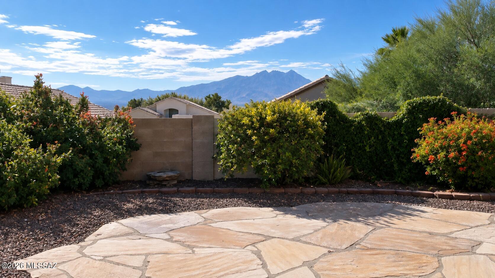 MOUNTAIN VIEWS, STYLISH UPDATES & EXCEPTIONAL CARE!  This gorgeous 3-bedroom, 2-bath home combines thoughtful updates, comfortable living spaces, and  mountain views in a convenient Green Valley location. Pride of ownership is evident in every detail, from the high ceilings and tile flooring throughout to the modern light fixtures and fresh exterior paint. Replaced windows and roof underlayment replaced approximately five years ago add even more value and peace of mind. Step inside to a spacious living and dining area filled with natural light. The kitchen offers granite countertops, a Bosch dishwasher, brand-new microwave, refrigerator approximately three years old, and a charming picture window above the sink. The adjoining breakfast nook creates the perfect spot to enjoy your morning coffee. Double doors open to the owner's suite with a bay window, walk-in closet, and beautifully remodeled en-suite bathroom featuring dual glass vessel sinks, modern fixtures, a stylish mirror, and an impressive tiled walk-in shower. Two additional bedrooms offer flexible space for guests, an office, or hobby room. The guest bathroom has also been tastefully remodeled with a glass vessel sink, custom metal-framed mirror, and also a beautiful tiled walk-in shower. Enjoy mountain views from the fully landscaped backyard, designed to attract hummingbirds and butterflies. The yard includes grapefruit and tangerine trees, decorative flagstone, and an irrigation system installed in 2021. Additional features include custom window coverings, a water softener, updated smoke detectors, washer and dryer, and abundant garage cabinetry. Conveniently located near shopping, dining and I-19. The Green Valley Recreation membership offers access to an incredible variety of amenities and activities, including fitness centers, pools, pickleball, art classes, and much more. Situated in a 55+ community, this home is ideal for year-round or seasonal living