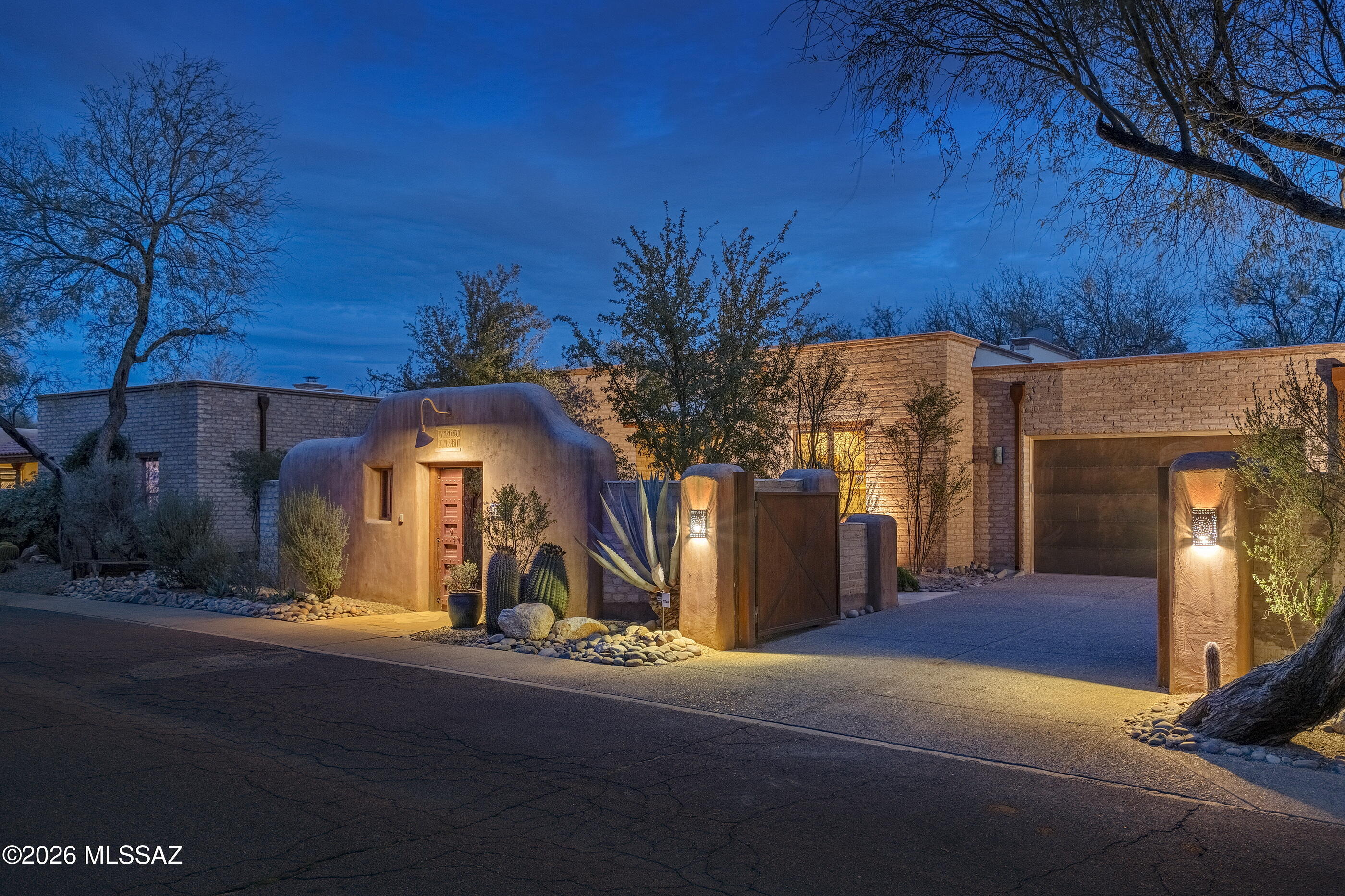 Centrally located in the Historic Ft. Lowell District, and privately set within the highly regarded ''Adobes Del Bosque'' enclave, this residence offers a composed and intentional expression of regional architecture. Sculpted plaster walls, mature native landscaping, and a measured entry sequence establish a sense of arrival that feels both restrained and enduring, underscoring a home rooted in craftsmanship and legacy. The interior is organized around proportion, texture, and light. Substantial 16 inch thick mud adobe walls provide a sense of permanence, while exposed timber beams introduce warmth and rhythm overhead. Terracotta scored concrete floors extend throughout the home, unifying the spaces and lending a quiet continuity that supports both daily life and moments of retreat. The main living room is centered around a masonry fireplace that feels integral to the structure. Carefully placed windows are deeply recessed within the adobe walls, offering framed views outward while preserving privacy through protective courtyard walls. Throughout the day, shifting light animates the plaster surfaces and wood elements, creating subtle changes in tone and atmosphere.

The kitchen and dining spaces are practical yet refined, with custom millwork and formed concrete countertops offering durability and restraint, while a central island anchors the room for gathering and preparation. The dining area opens directly to the south facing covered patio, allowing meals and entertaining to move easily between interior and exterior spaces.

Sleeping and working areas are thoughtfully separated from the main living areas. The primary suite occupies the southwestern end of the home, offering privacy and generous scale, with a bath that continues the palette of adobe, plaster, concrete, and wood. An additional en-suite bedroom is seamlessly integrated, ideal for family or guests while preserving the clarity of the overall plan. A third bedroom features built-in bookcases and an integrated desk, allowing it to function effortlessly as a bedroom, office, or flexible living space.

The covered patio functions as a true extension of the home, defined by substantial beams and enclosing walls that create shade and comfort year round. Beyond, the backyard opens to a protected preservation area where the land remains intentionally untouched. Winding quietly through this landscape is the historic Corbett Irrigation Ditch, an early lifeline that once carried water from Tanque Verde Creek to the old Fort Lowell. This enduring ribbon of history adds meaning to the setting, connecting the home to the earliest patterns of settlement and cultivation in the region. 

Encompassing 2,671 Sq Ft of living space, this residence presents a rare opportunity to acquire a thoughtfully designed desert home that values privacy, material integrity, and quiet confidence within one of the area's most desirable communities.