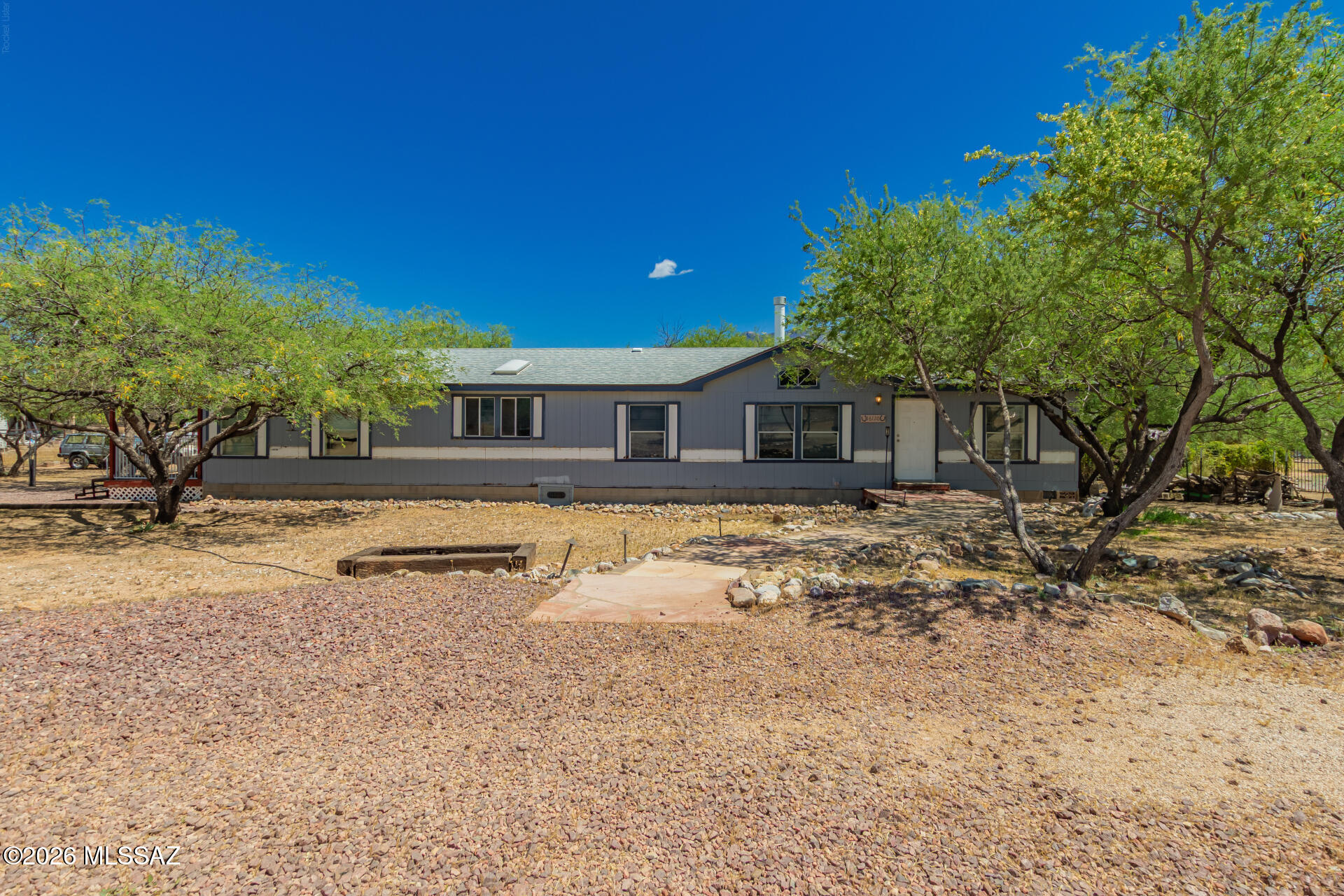Incredible opportunity to own 1 acre of horse property with breathtaking Catalina Mountain views! This 4BD/3BA manufactured home features a spacious open floor plan with vaulted ceilings, abundant natural light, and a cozy fireplace with built-in shelving that anchors the main living area. The split bedroom layout offers flexibility for multi-generational living or guests, while the kitchen includes an island and generous cabinet space ready for your personal touch. Surrounded by mature desert trees and natural landscaping, the property provides privacy, shade, and a peaceful setting with plenty of room for horses, RVs, toys, or future expansion. With solid bones and endless potential, this is a rare chance to create your own desert retreat or investment in a highly desirable area--bring your vision and make it shine!