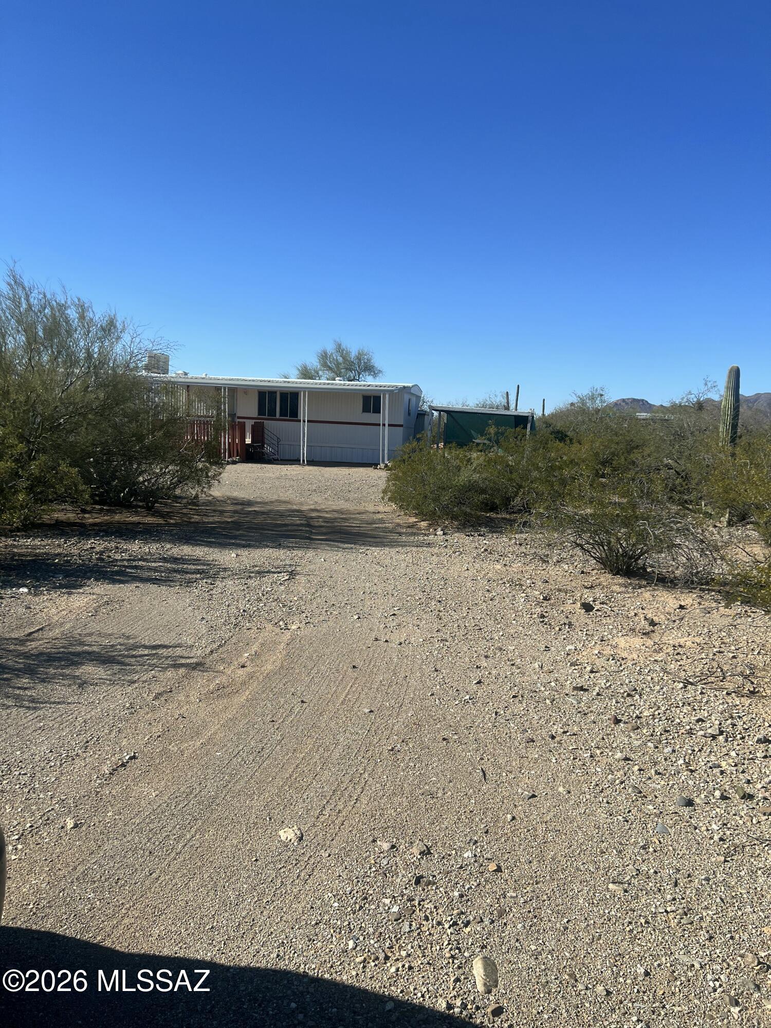 Peaceful desert setting. One flat acre with 2 bedroom, 1&1/2 bath home. All new paint, flooring, kitchen cabinetry & sink, evaporative cooler, and new toilets. Updated electric. Two large awnings were converted into living space, not assessed in county records. Shed has hookup and washing machine. Beautiful mountain, sunrise, and sunset views. Fully fenced on three sides with wash bordering unfenced north edge of property. Gated entry with circular driveway. Space for many uses. Clean and move in ready!