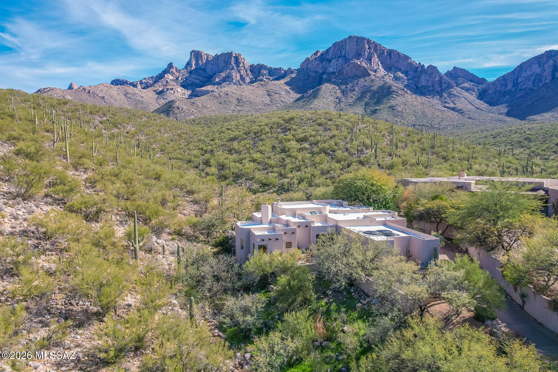 STRIKING CUSTOM SANTA FE in guard gated La Reserve backs to the rolling hillside affording spectacular Pusch Ridge views and a resort style yard. Luxury details throughout lend a rustic feel including soaring woodbeamed ceilings, flagstone tiled floors in main living areas, Travertine floors & shower surround in baths, solid wood cabinetry & doors, art & media alcoves plus 3 cozy fireplaces, 4 bay windows and multiple illuminating skylights. Affording 3 bedrooms, 2 baths and 3,166 sq ft of gorgeous living space, the charming courtyard entry with trickling water feature flows to a grand Living Room with stacked stone fireplace and floor-to-ceiling view windows. Gathering room beyond features curved view windows, distinct living & dining areas, plus gourmet island kitchen with granite and stainless amenities, work desk and large walk-in pantry. Private Owner's Suite with fireplace and plank tile flooring hosts a luxury spa bath with jetted tub, Travertine tiled shower, dual vanities and custom walk-in closet. Adjacent lies a spacious library/office with custom built-ins and views. Bedroom 2 off center hallway offers ensuite bath with dual entry while third bedroom lies off kitchen hall and laundry room. Additional amenities include security system, central vacuum plus wired sound inside & out. Extended garage offers 2 storage rooms (one with workbench & cabinets) plus double door, shelved storage closet. Retreat outdoors to a flagstone paver patio, heated pool with raised spa waterfall, outdoor kitchen, kiva fireplace, rejuvenating sauna plus breathtaking views. A perfect desert retreat for the most discerning buyer!