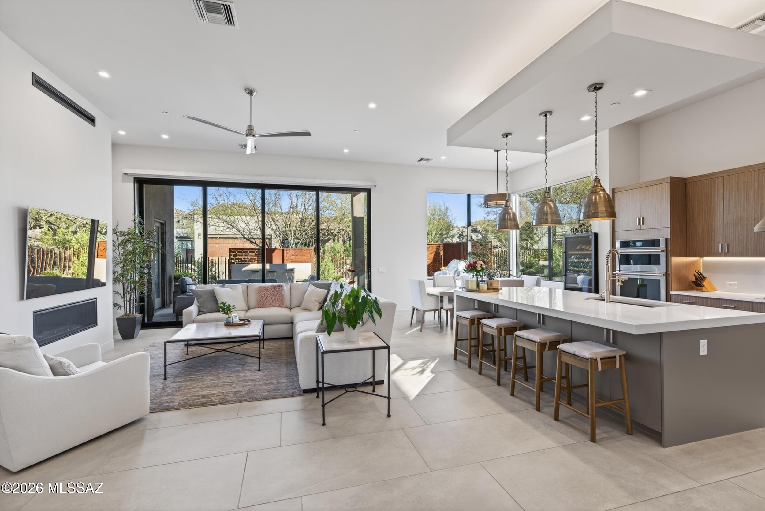 Tucked inside the prestigious Stone Canyon community, this semi-custom contemporary residence offers a seamless indoor-outdoor living experience with refined, high-end finishes throughout, just a short distance to the clubhouse and driving range. Featuring 3 bedrooms, 3.5 baths, and a flexible office/bonus space, every bedroom includes its own private en suite, ideal for comfort, privacy, and hosting.
A spacious open-concept layout welcomes you with soaring 12' ceilings, a stunning gas fireplace, and oversized 10' sliding glass doors that open to an extended covered patio with tile flooring that flows beautifully outdoors. The gourmet kitchen is designed to impress with stainless steel appliances, luxury finishes, and a massive center island perfect for entertaining. Step outside to a to a fully landscaped backyard oasis complete with a tranquil fountain and built-in outdoor grill, creating the perfect setting for Arizona living. Additional highlights include a whole-home water system, an extended garage on one side for extra storage or flexibility, a custom office build-out in one of the bedrooms, and custom garage cabinetry for exceptional organization and functionality.

Modern design. Luxury details. Prime Stone Canyon location.