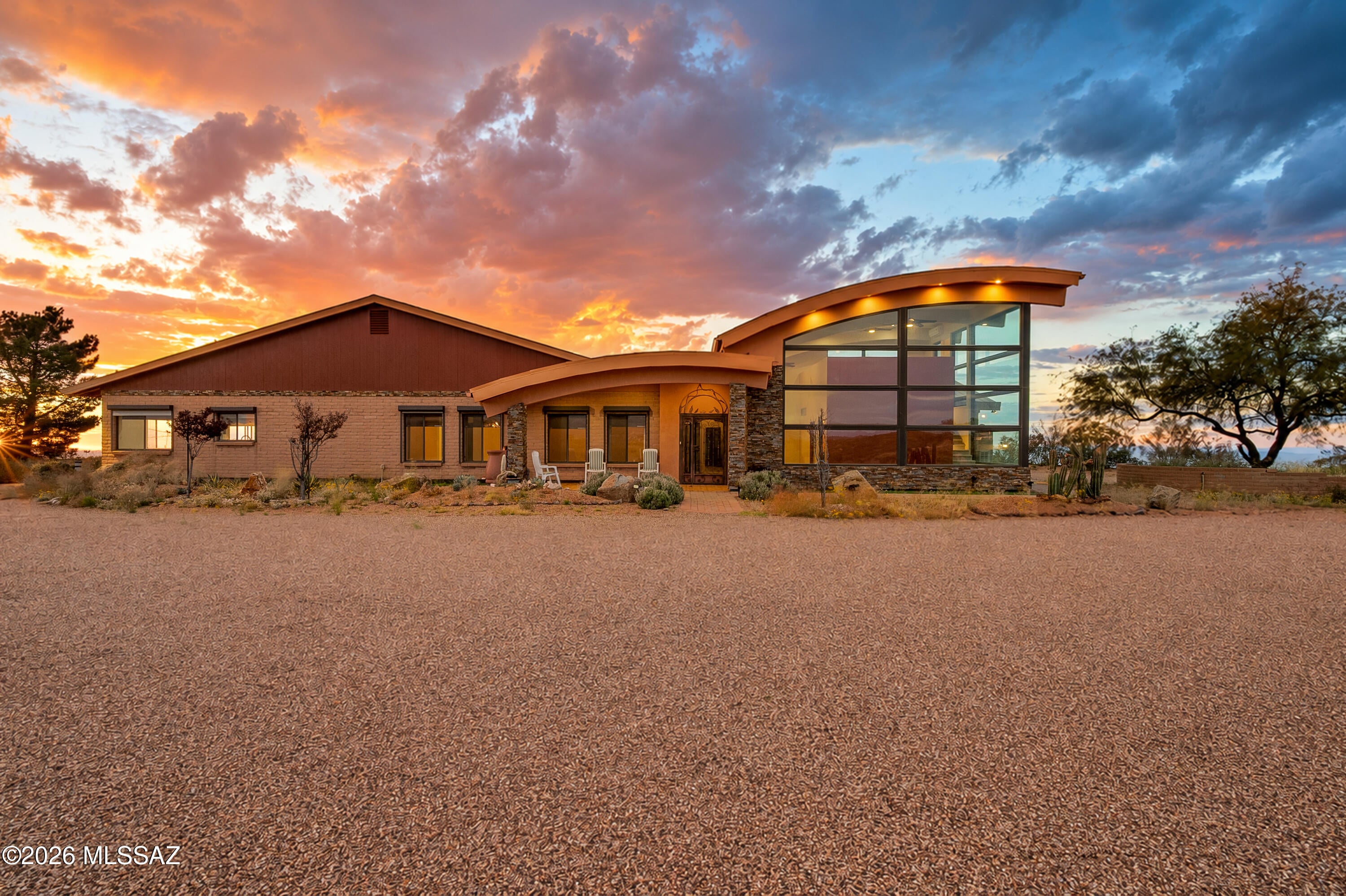 Discover an extraordinary opportunity to own a truly remarkable custom estate perched at one of the highest vantage points in Oracle, Arizona, where breathtaking 360-degree panoramic  mountain views, unparalleled privacy, and the natural beauty of the Sonoran Desert create an exceptional living experience. Situated on an expansive 5.28 acres encompassing TWO separate parcels included in the purchase price, this magnificent 3,596-square-foot residence offers an extraordinary combination of luxury, versatility, functionality, and endless possibilities. From the moment you arrive, you will appreciate the property's commanding hilltop setting, overlooking the charming town of Oracle and showcasing spectacular mountain ranges stretching across the horizon. Whether you envision a private desert sanctuary, an equestrian retreat, a multigenerational family compound, or simply a peaceful escape surrounded by nature, this one-of-a-kind property presents an opportunity that is increasingly difficult to find.

Thoughtfully designed to embrace its remarkable surroundings, this beautifully renovated four-bedroom, three-bathroom residence showcases an abundance of natural light, impressive architectural details, and carefully selected upgrades throughout. Expansive windows invite the outdoors inside, framing picturesque desert landscapes and mountain vistas while creating an atmosphere of warmth, openness, and tranquility. The home's inviting interior features beautifully updated kitchens and bathrooms, custom cabinetry, soft-close cabinet features, upgraded finishes, and thoughtful improvements that reflect attention to detail. Generously proportioned living spaces provide an ideal balance of everyday comfort and effortless entertaining, while a versatile bonus area offers the flexibility to accommodate a private home office, fitness studio, hobby room, or additional recreational space.

One of the home's most captivating features is its beautiful sunroom, where expansive windows invite abundant natural light and provide an exceptional setting to appreciate the surrounding desert scenery throughout the changing seasons. Imagine beginning each morning with a fresh cup of coffee as the sun rises over the mountains, enjoying the peaceful atmosphere and cooler temperatures that Oracle's higher elevation has to offer. As evening approaches, watch the Catalina Mountains transform into magnificent shades of pink, orange, and purple while the setting sun illuminates the surrounding landscape. With sweeping views in virtually every direction, the beauty of this property is something that must truly be experienced in person.

Adding another remarkable dimension to this estate is the impressive 896-square-foot guest addition, distinguished by dramatic floor-to-ceiling glass that beautifully captures the surrounding mountain scenery. This exceptional space offers tremendous flexibility for accommodating extended family, visiting guests, or multigenerational living arrangements. Its abundance of natural light and captivating views create an inviting environment that feels both connected to the main residence and immersed in the surrounding landscape.

For automobile enthusiasts, collectors, hobbyists, and those requiring substantial storage, this property offers an extraordinary amenity rarely found in residential real estate: EIGHT TOTAL GARAGE SPACES! The main residence provides garage accommodations for up to five vehicles, while the substantial detached garage offers additional parking for three vehicles, along with versatile space capable of accommodating larger equipment, a tractor, or even a Sprinter-style van. Whether you own recreational vehicles, classic automobiles, off-road equipment, or simply desire exceptional workshop and storage possibilities, this property offers the flexibility to support a wide variety of lifestyles and interests.

Beyond its impressive interior and garage accommodations, this estate has been thoughtfully equipped with features designed to enhance durability, security, and long-term functionality. Notable improvements include protective rolling shutters, reinforced doors, a durable standing-seam metal roof, and leaf-filter gutter systems. An attached greenhouse provides an exciting opportunity for gardening enthusiasts to cultivate plants and enjoy year-round horticultural pursuits, while established mature fruit trees contribute to the property's distinctive character. A rainwater harvesting system further complements the estate's connection to its natural desert surroundings.

The expansive acreage is equally impressive, presenting an exceptional opportunity for those seeking privacy, recreational freedom, and room to pursue their passions. Equestrian enthusiasts will appreciate the horse-friendly acreage, offering potential for creating a personalized horse property with thoughtfully planned improvements. The property's elevated setting and generous land area also offer possibilities for additional outdoor amenities, recreational spaces, and a potential helipad location, subject to applicable approvals and regulations.

Perhaps one of the most compelling features of this offering is the inclusion of TWO SEPARATE LAND PARCELS, creating an additional level of flexibility and long-term potential. The second parcel presents an exciting opportunity to explore the possibility of constructing an additional guest residence, subject to zoning, permitting, and applicable building requirements. Imagine creating your own private family compound, with separate accommodations for loved ones while maintaining the privacy and independence that makes estate-style living so desirable. The possibilities are as inspiring as the property itself.

Outdoor living is truly at the heart of this extraordinary residence. Enjoy the serenity of wide-open spaces, the refreshing mountain breezes, and the captivating beauty of Arizona's high-desert landscape. Oracle's elevated setting offers a welcome retreat from the warmer temperatures of the Tucson Valley, creating an inviting environment for enjoying the outdoors and appreciating the area's distinctive natural surroundings. From spectacular sunrises and vibrant sunsets to peaceful evenings beneath expansive star-filled skies, every day presents another opportunity to experience the extraordinary beauty of this remarkable location.

Properties offering this combination of substantial acreage, commanding panoramic views, extensive garage accommodations, beautifully renovated living spaces, a distinctive guest addition, and two included parcels are truly exceptional. This is more than simply a residence; it is an opportunity to embrace a lifestyle defined by privacy, natural beauty, versatility, and the freedom to create something uniquely your own.

Experience the pinnacle of elevated desert living in Oracle, Arizona. Schedule your private showing today and discover firsthand the breathtaking views, exceptional amenities, and remarkable possibilities awaiting you at this one-of-a-kind hilltop estate!