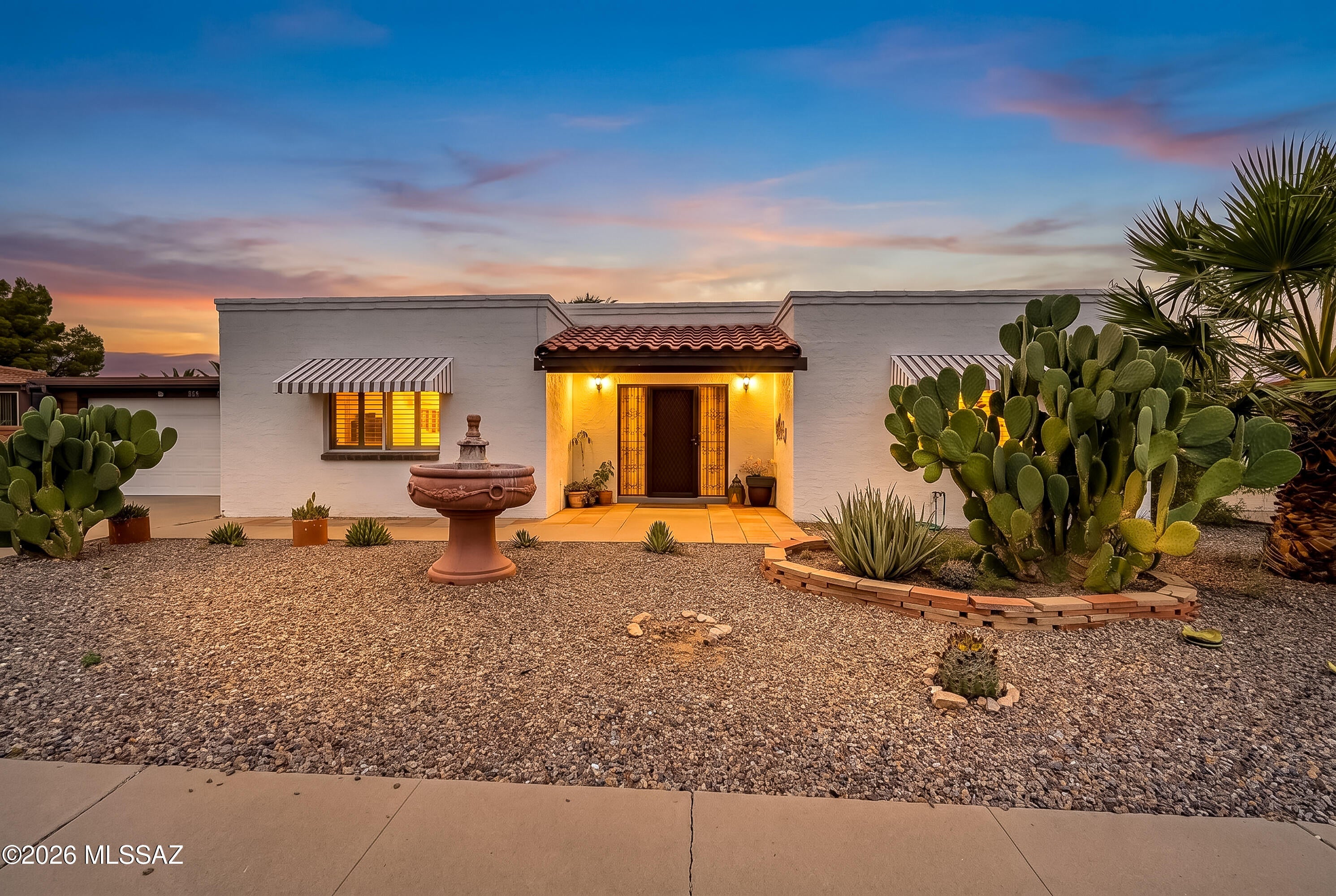 Distinctive finishes, a spacious Arizona room, and a private backyard bring character and comfort to this Green Valley home. Located in a designated 55-and-over community near the Country Club of Green Valley, shopping, and I-19, this 2-bedroom, 2-bath residence offers 1,300 square feet plus a tiled 400-square-foot Arizona room not included in the stated living area. This versatile space provides additional room for gatherings, hobbies, or relaxation. The kitchen features gray cabinetry, granite countertops, a blue tile backsplash, stainless steel appliances, and pantry storage. Updated bathrooms feature vessel sinks, a dual-sink vanity, and a glass-enclosed shower with striking tilework and mosaic accents. Ceramic tile throughout and bedroom shutters complement the interior. - A spacious laundry and storage room houses the washer and dryer, while a roomy workshop and an extended 2-car garage with a work area and storage offer space for projects and organization. A paved back patio opens to an attractive, private backyard for outdoor dining and relaxing.  Schedule a showing to explore this home's distinctive details and versatile spaces.