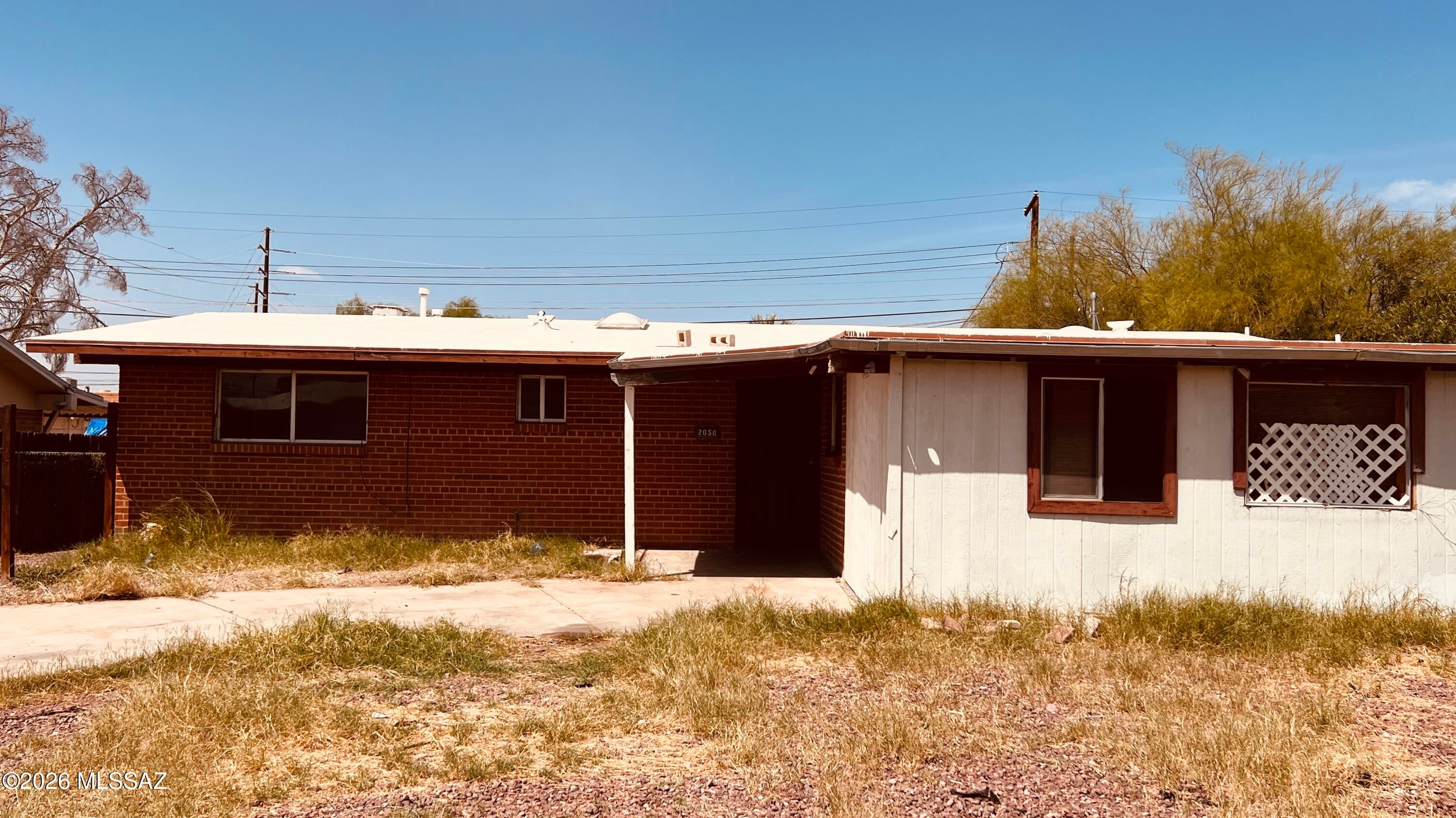 FIXER - upper. Brick home with fenced back yard. Great neighborhood for attending Flowing Wells schools.  West/Central neighborhood, close to Tucson Mall, Silverbell Golf Course, Northwest Medical Center.  Home features a good sized lot with block and chainlink fencing.  3 bedroom 2 bath with living rooms, dining area and open kitchen with nice 5x5 saltillo-look tile. Family room Laundry room with exit to side yard. Ceiling fans help with airflow. Front drive has plenty of room to park a few cars in carport. Past rental of 15 years. Neighborhood is nicely kept.  Fruit tree in backyard. Property is being sold as-is, No Repairs. County Assessor lists home at 1696 sqft, if square footage is a material matter to buyer, it must be investigated during the inspection period.