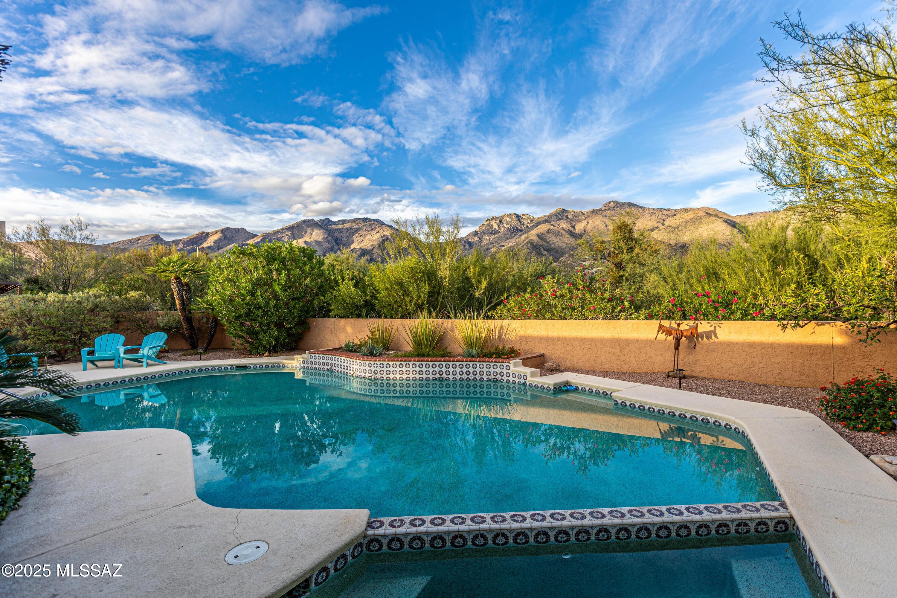 Welcome to this stunning residence nestled in the desirable Cimarron Foothills community, within the acclaimed District 16 schools. Enjoy majestic Catalina Mountain views, owned solar, and new zoned HVAC for year-round efficiency and comfort. This spacious 4-bedroom, 3.5 bath home features elegant upgrades throughout, including two remodeled bathrooms, electric shades, and four security doors for peace of mind. The great room offers soaring ceilings, a cozy fireplace, and direct access to covered patio overlooking an oversized pool surrounded by lush, mature landscaping with citrus trees. The chef's kitchen impresses with an abundance of cabinetry, granite counters, built-in refrigerator, breakfast bar, and sunny nook. A formal dining room and large living room proivde versatile spaces for both entertaining and everyday living. Retreat to the oversized primary suite, complete with patio access, a jetted soaking tub, spacious walk-in closet and a tranquil atrium just off the bath - your own private oasis. Additional highlights include a front courtyard, brick paver driveway, laundry room with cabinets and sink, and community security patrol. Located just minutes from upscale shopping, dining, and restaurants in the Catalina Foothills, and near an award-winning elementary school where the joyful sounds of children at play fill the air. Experience the best of Tucson living- mountain views, resort-style outdoor living, and timeless Foothills elegance all in one exceptional home.