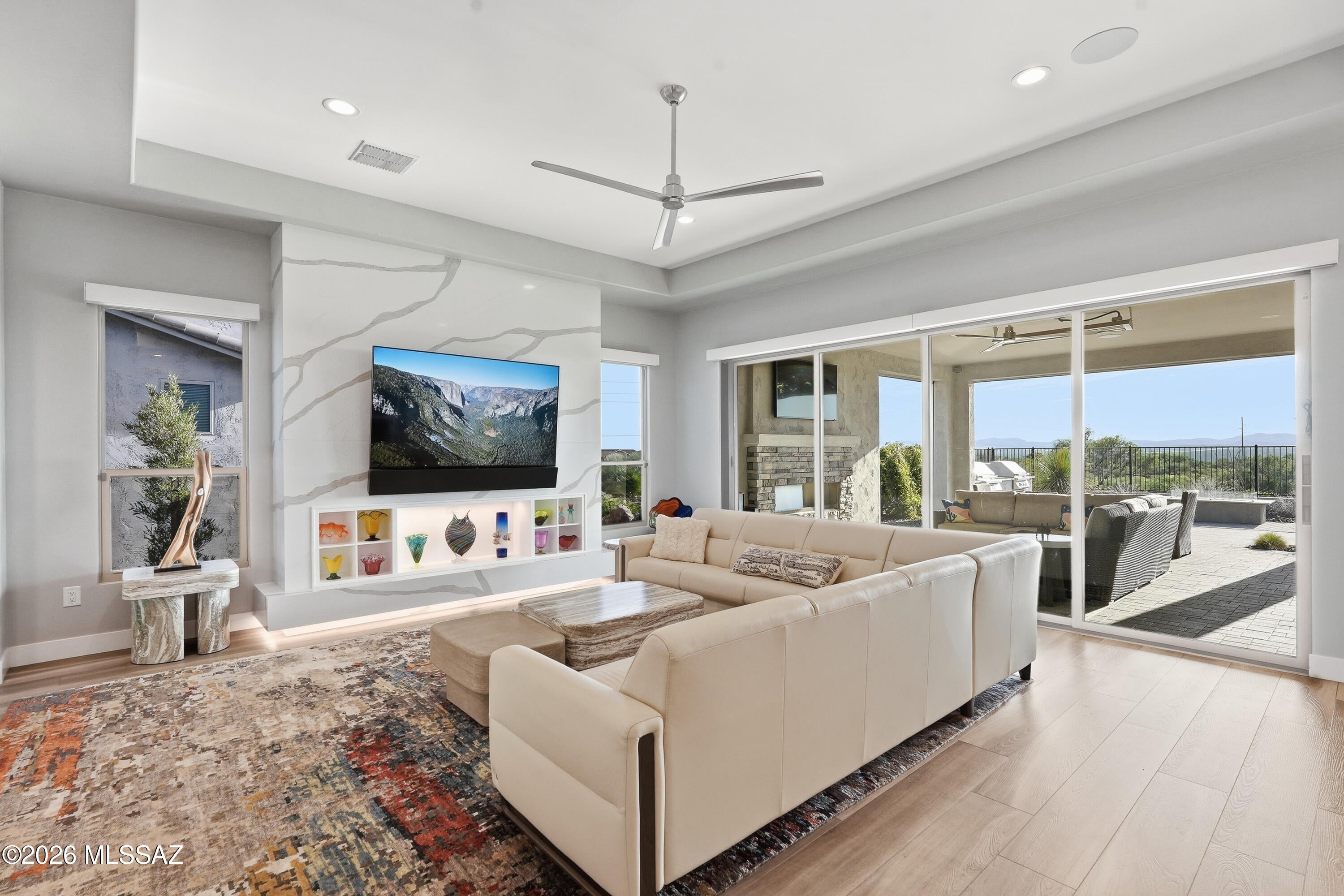 Set against open desert with the Tortolita Mountains filling the horizon, this Avalon is the most significant residence ever offered at SaddleBrooke Ranch - and the moment the iron front door opens, you understand why. A single-slab marble accent wall anchors the great room. A sixteen-foot four-panel glass wall disappears, and there is no line between the coffered-ceiling interior and the desert beyond. Sunset does the rest.

The backyard is built for year-round use. An extended covered patio runs the length of the home. A stone-faced fireplace with TV, a marble-topped firepit, a custom water feature, and a built-in BBQ with high-end smoker, grill, and marble counters. Ceiling speakers overhead, a 61'' Infratech heater for winter evenings, turf, uplighting, a dog run, and a view fence wi a private gate opening onto the desert trails.

Inside, a Crestron system runs lighting, music, cameras, shades and climate by time of day and season - from the wall, your laptop, or your phone, from anywhere in the world. A 400 AMP panel supports it. The LG Signature kitchen carries a six-burner pro cooktop, combination speed oven, 42-inch built-in refrigerator, quartz waterfall island, full-height backsplash, butler's pantry, coffered ceiling, and reverse osmosis. The great room wet bar answers with Zephyr wine fridge and beverage fridge. The dining room wears a split-face white marble wall with lit floating shelves.

The primary suite opens to the patio through a three-panel slider and retreats behind a pocket door to a spa bath: extended curbless shower with custom tile, three shower heads, Toto Neorest toilet, and an extended organized closet. Two guest suites follow suit - custom tiled walk-in showers, marble counters, one with 11' ceilings. A den with a custom mural wall and 85" Sony Bravia TV. A powder room finished like the rest.

The details never lapse: LVP flooring throughout, 5" baseboards, 8' solid-core two-panel doors, two-tone paint, matte black fixtures, upgraded hardware, seamless rain gutters, stone-accented Design D front elevation, pavered driveway and walkway.

The extended three-car garage is climate-controlled by mini-split, epoxy-floored, insulated, and fitted with premium cabinets, workbench, slat wall, overhead racks, Tesla charger, and Kinetico saltless softener behind carriage doors. The extended laundry room includes a custom tiled dog wash with handheld shower, and LG black steel front-loaders on pedestals.

Built to order with roughly one hundred builder options, and finished since with $395,250 in improvements.