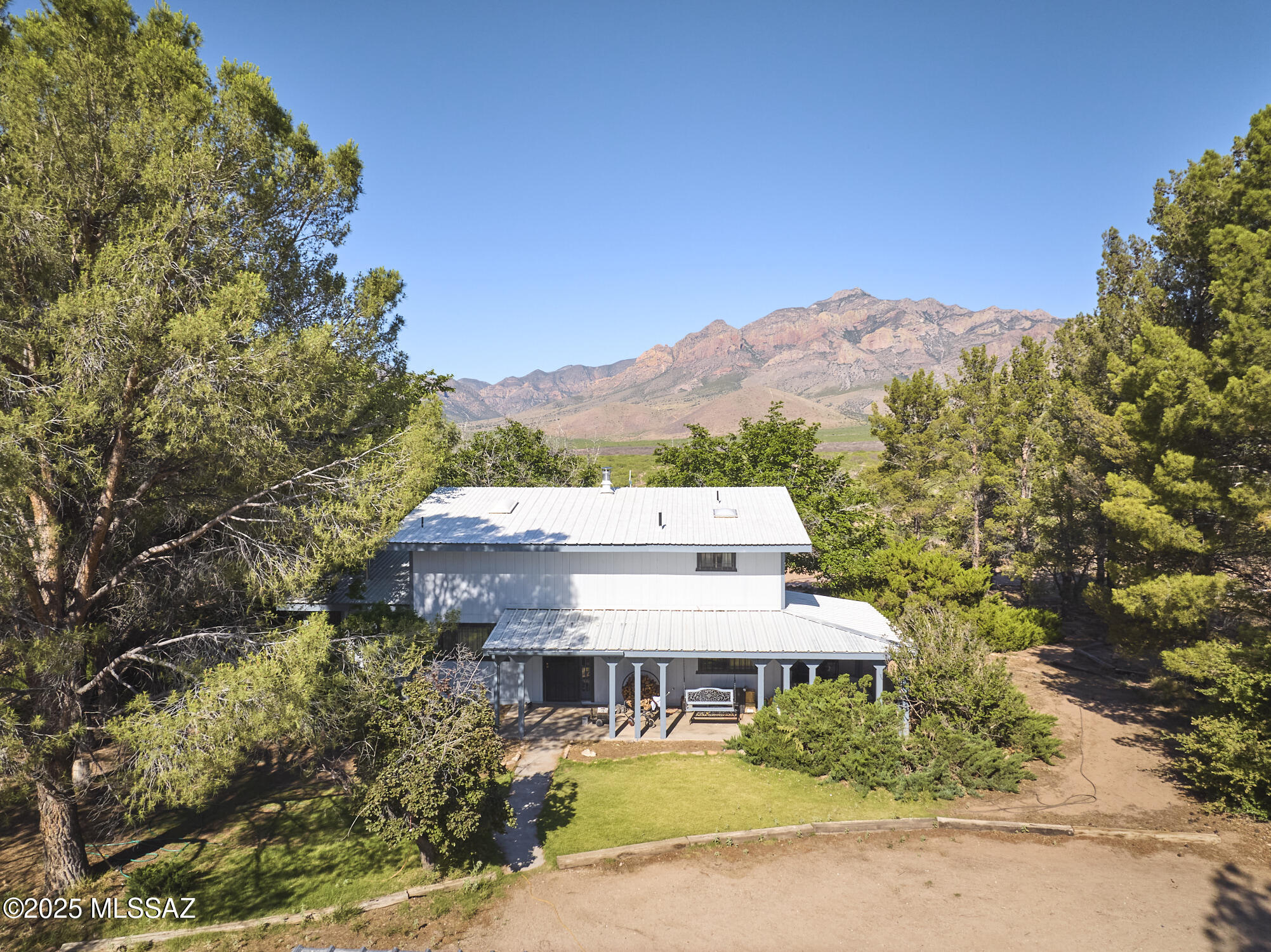 Enjoy mountain views, mature trees, and room to roam on this 38.98-acre horse property in Portal, AZ. This 1,802 sq. ft. two-story home features an open living and dining area, kitchen, guest bath, and a private bedroom suite with its own entrance--ideal for guests, multigenerational living, or rental potential. Upstairs loft with bathroom offers flexible space for an office, studio, recreation room, or additional bedroom. Wraparound porch overlooks the Chiricahua and Peloncillo Mountains. Property improvements include a carport, hobby shop, 60' round pen, corrals, hay barn, loafing barn, garden area, fire circle, shooting range, stone pathways, and multiple outdoor seating areas. Minutes from Cave Creek Canyon, restaurants, galleries, hiking, and world-renowned birding.