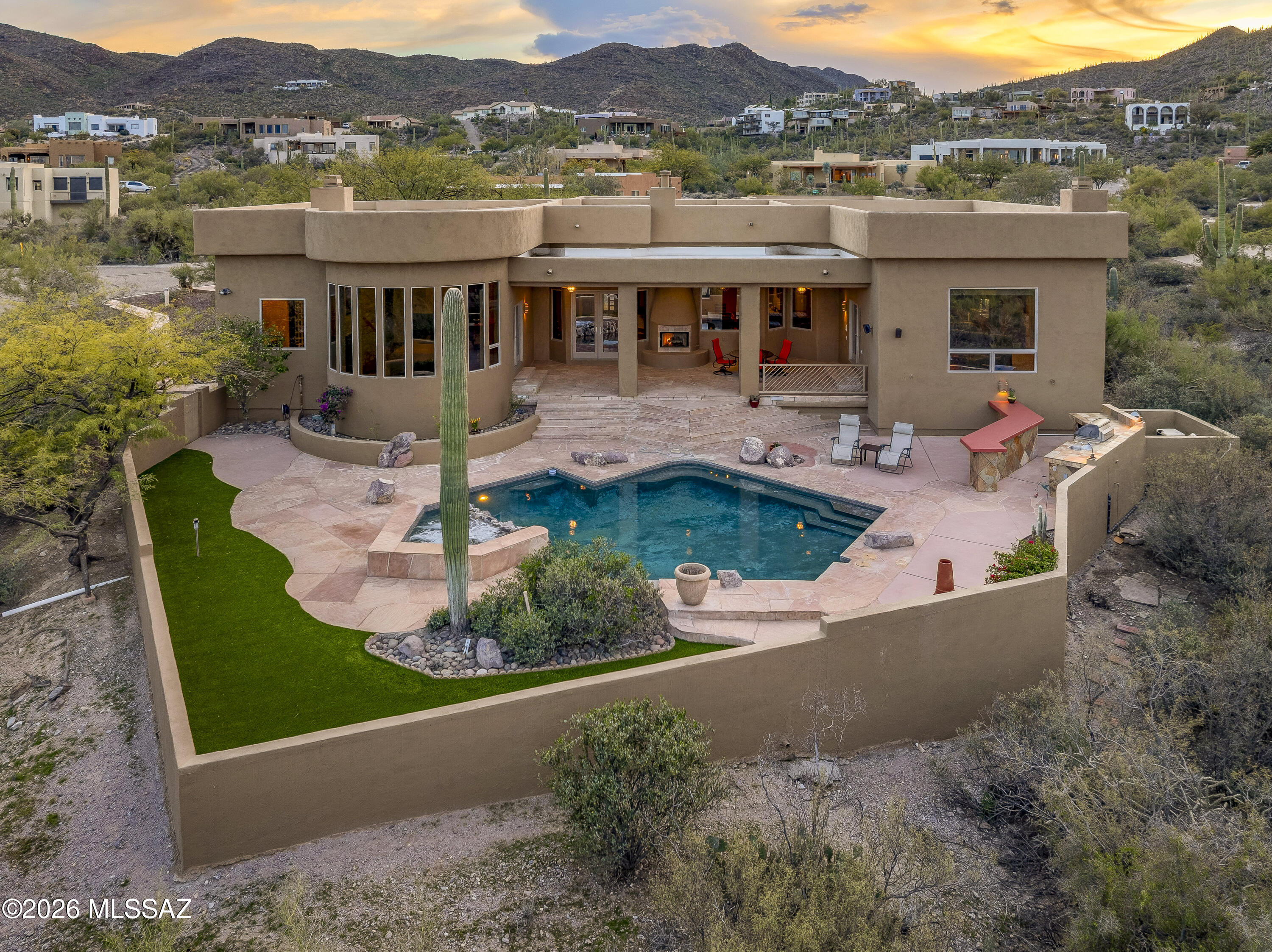 A rare and refined desert estate where architectural artistry, privacy, and panoramic beauty converge in extraordinary harmony!
A Superb Southwestern contemporary estate masterfully designed and built by Talavera Homes, gracefully positioned on a rare 1.03 acre homesite adjoining and overlooking Tucson Mountain Park and just minutes from Renowned Gates Pass. Set within the intimate enclave of Paseo Montana on Tucson's coveted West side, this remarkable residence captures unobstructed panoramic vistas stretching from the Tortolita Mountains to the Catalinas and onward to the Rincons, with mesmerizing city lights! 
Spanning 3,520 sq ft, this 4 bedroom, 4 bath home includes an office/ library/exercise room within a thoughtfully designed split floor plan that offers both privacy and seamless livability. Beautifully crafted glass front entry opens to a grand foyer where soaring ceilings, expansive windows, and radiant natural light immediately draw your attention to the breathtaking desert /City backdrop. Elevated finishes throughout include soaring coffered ceilings, natural stone, flagstone floors, Anderson windows and doors, lighted niches, and solid core custom interior doors that reflect enduring quality and architectural distinction. 
A spacious Living room/den invites you to sit and enjoy the View! A double-sided fireplace and grand dining area convey warmth and a sense of home. Did I mention every window has a view? Yes, every window. 
The heart of the home unfolds in your stunning open concept kitchen and living space designed for refined entertaining and inspired daily living. Your new custom kitchen by Southwest Kitchen and Bath showcases rich cherry cabinetry with pull outs for spices, pull up shelving for appliances, pantry cabinetry, and mesmerizing Volcano granite paired with a natural stone backsplash. A substantial island with generous bar seating invites gathering and conversation. Premium appliances include an LG Studio built in refrigerator with WiFi, KitchenAid gas cooktop with downdraft venting, Bosch dishwasher, Wine cooler and Beverage refrigerator. Adjacent is a flexible space which offers the opportunity for intimate dining or a tranquil reading retreat. Seamlessly connected, the living room is both dramatic and welcoming, anchored by a fireplace and framed by expansive picture windows that provide front row seats to never ending natural beauty. Enjoy panoramic mountain and city views mirroring those from the den, dining room, and primary suite. Experience jaw dropping sunrises, spectacular sunsets, tranquil moon watching, brilliant stargazing, and the drama of monsoons rolling across the valley. In winter, marvel at the snow dusted peaks of the majestic Catalina Mountains. Nature's ever changing colors create a living masterpiece beyond every pane of glass!!
Your primary suite is a private sanctuary defined by a breathtaking custom Segmented Radius window wall overlooking saguaro studded parkland, city lights, and sweeping mountain vistas. A romantic 2-sided fireplace enhances the ambiance, while your spa-inspired bath features a jetted soaking tub, separate glass block shower, dual vanities with dedicated makeup station, plus two spacious walk in closets.
Bedroom 2 and the office share a beautifully appointed Jack and Jill bath with tub. Down the hall off the kitchen, Bedroom 3 is positioned near a full bath with convenient hall access ideal for guests and a pocket door to the bedroom. Bedroom 4 serves as a private ensuite retreat with its own bath which features a steam shower!
Outdoor living is equally exceptional. The vast covered patio with fireplace creates an inviting setting for year round enjoyment. A sparkling heated pool and waterfall spa, and built-in grill with bar seating complement the commanding 180+ degree views across the valley and city below.Fully fenced and with turf- safe and ready for kiddos and pets. Supreme privacy and quiet define this desert oasis.
Additional amenities include a spacious laundry room with sink, an oversized three car garage, and generous exterior space with room for extra parking or RV access. Recent updates include exterior paint, a new driveway, new kitchen to include pantry cabinetry, Kinetico water softener, east side furnace, A/C and water heater,  Pentair gas pool heater, plank flooring in two bedrooms and custom closet cabinetry, reflecting thoughtful enhancements and meticulous care.
A true gem of a location just minutes from Gates Pass,  Tucson Mountain Park literally your backyard, and in close proximity to Saguaro National Park West, Arizona-Sonora Desert Museum, and Old Tucson, this exceptional property offers immediate access to hiking, biking, and the natural beauty that defines Tucson living, while remaining just ten minutes from downtown's vibrant dining and cultural scene. Extensive Trails system is just minutes away in all directions- Feliz Paseos, Painted Hills, Sweetwater Preserve, Camino de Oeste, David Yetman/Gates Pass to name a few! DMAFB, Tucson Airport, Raytheon, Caterpillar, hospital, UofA, supermarkets/dining options- all within reasonable driving distance.  
Heading home at sunset becomes a daily ritual of serenity you will get used to pretty quickly! Come experience relaxed Luxury today.