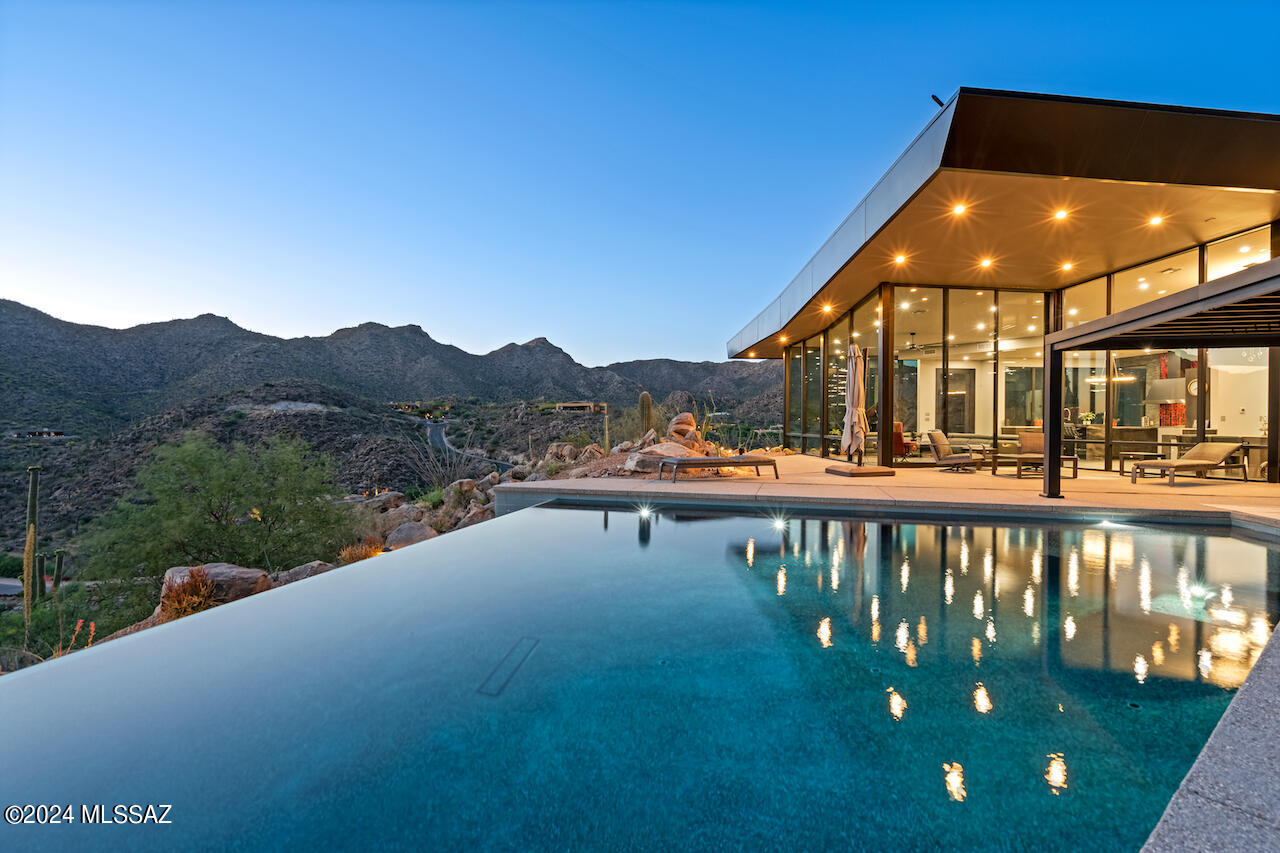 This home closed INCLUDING the vacant located at 15090 N Dove Canyon Pass & all furnishings. Come visit this custom Desert Modern residence within the man-gated community of Canyon Pass at Dove Mountain. Situated on a gentle rise above other neighboring homesites, this 9+ acre residence is positioned within large Sonoran Desert rock outcroppings providing unobstructed views in all directions. The 'open floor plan' was designed by Mark Soloway w/high ceilings + oversized floor to ceiling glass panes. The residence provides unlimited views yet creates a feeling of privacy and exceptional solitude. High end finishes throughout this custom masterpiece include Subzero/Wolf appliances, Lutron shades and comes fully furnished including a baby grand piano, artwork and electronic accessories a secluded office w/wonderful views. Lower level also hosts an oversized 4 car garage, along with a separate 'bonus/exercise room' with universal gym and workbench area which is uniquely air conditioned. The private yet entertaining outdoor living space is complimented by a negative edge Pebble Tec pool, a rooftop waterfall feature, shaded ramada areas, and a linear gas fire pit. Up the spiral staircase is a "skydeck' great for stargazing, bird watching & overall nature viewing. Offered fully furnished - this is a fabulous package for this extraordinary home. Dove Mountain is a 2025 Readers' Choice contender for Best Master-Planned Community. Enjoy Dove Mountain's world class golfing, outstanding hiking trails, biking paths, state of the art sports club, casual and fine dining options. Easy access to theatre and arts, University of Arizona campus and multiple airports. Sonoran Desert living at Dove Mountain means enjoying outdoor living at its best.  Nearly 1/3rd of Dove Mountain's 6,200 acres of desert splendor is being kept in perpetuity as natural open space. More than 10 miles of its boundary borders other formal preserves or Arizona State Trust-owned mountain land. That lovely "cooing" sound you hear in the evenings may be the gentle Inca Doves which live in the area and give this elegant enclave its name. Pima County's 3,000-acre Tortolita Mountain Park borders Dove Mountain to the north. To the south is the 2,400-acre Tortolita Preserve, with its outstanding biking and hiking trails, designated to be permanently sustained by the City of Marana and the State of Arizona. Nestled in the beautiful Tortolita Mountain Foothills, Dove Mountain is perhaps the epitome of Southwest desert living. The temperate climate allows residents to enjoy an indoor/outdoor lifestyle virtually all year-round, not just in in the late fall, winter and spring seasons for which the region is famous. The wildlife of Dove Mountain is fascinating. The Sonoran Desert is home to species like the Great Horned Owl, the Golden Eagle, the Black-chinned Hummingbird, Gambel's Quail, the Hooded Oriole and the Cactus Wren, Arizona's official bird. The lifestyle here is fascinating, mesmerizing, graceful, luxurious and fun. Perhaps your own Dove Mountain story is just beginning at THIS outstanding, peaceful fine Soloway Designed modern contemporary custom home. Call for a private showing.