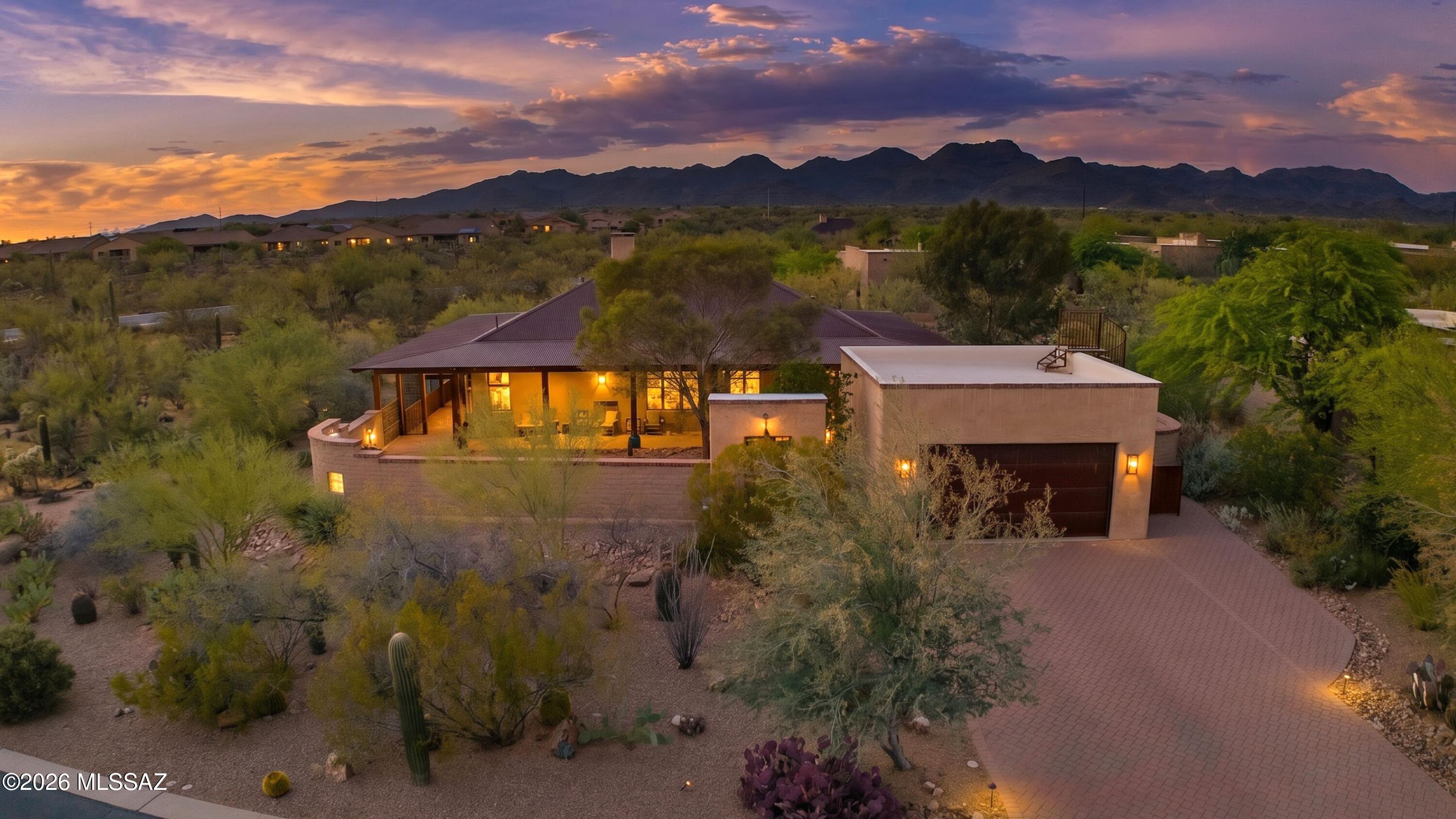 Tucked into a protected natural desert setting in coveted Sky Ranch, this extraordinary mud adobe residence--designed by renowned builder Stellar Gray--blends Australian Queenslander architecture with influences from Mexico, Spain, India, and the American Southwest. With an Open Floor Plan, 3 Bedrooms and 2 Bathrooms, it is constructed with 16-inch-thick mud adobe walls designed for exceptional thermal mass, the home is a rare fusion of artisan craftsmanship, architectural authenticity, and modern luxury.A corrugated metal roof, expansive covered wraparound verandas, exposed tongue-and-groove wood ceilings, steel casement doors and windows, plaster walls, wood lintels, and solid alder doors create a timeless architectural presence throughout. Enter through handcrafted antiqued double doors into a private courtyard oasis featuring a sunken beehive firepit, mature desert landscaping, uplighted saguaros, raised garden beds, and tranquil gathering spaces surrounded by protected preserve land for exceptional privacy and serenity. Designed for seamless indoor-outdoor living, every bedroom and living space opens directly onto the deep wraparound patio through individual steel casement doors with separate screen doors, allowing cooling breezes to flow throughout the home in true zaguan style. The heavy-gauge screened porch system offers year-round enjoyment of the surrounding desert landscape while keeping critters out.

Inside, the open-concept great room is both dramatic and welcoming, anchored by a gas beehive fireplace beneath soaring vaulted wood ceilings. The kitchen combines warmth and sophistication with knotty alder cabinetry, concrete countertops, walnut butcher-block island, walk-in pantry, induction range with warming drawer, Electrolux convection oven, and stainless appliances.
The luxurious primary suite features tongue-and-groove ceilings, walk-in closet, barn door entry to the ensuite bath, dual vanities, and a custom walk-in tiled shower with deep niches. Secondary bedrooms offer versatility for guests, offices, or creative spaces. Additional highlights include sealed concrete flooring throughout, recessed lighting, gallery-style hallways, custom hand-laid tile work, full-sized laundry room with built-ins, 2-car garage with extensive storage and epoxy coated foor. And, a spiral wrought-iron staircase leading to a rooftop viewing deck with panoramic mountain and city-light views stretching to downtown Tucson--perfect for Fourth of July fireworks.
Nearby Tangerine Sky Community Park has a playground, shade structures, walking trails, bathrooms, and a dog park!
Set on a premium .38-acre corner homesite enveloped by preserve land, this architecturally significant home offers a rare opportunity to own a true desert masterpiece.