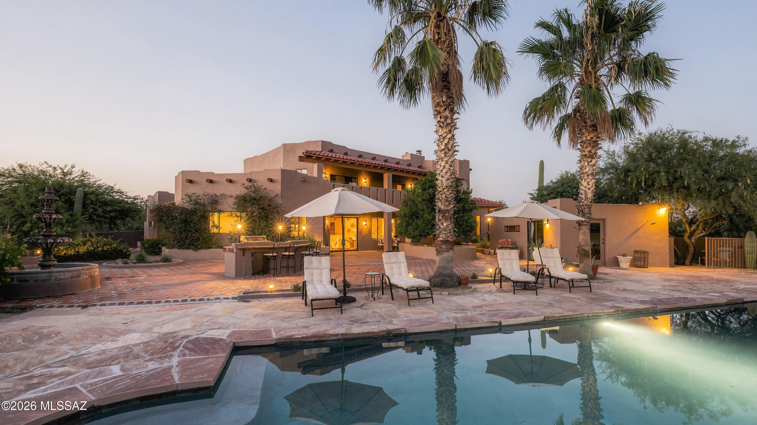Pasos del Cielo - A Timeless Southwestern Hacienda
Welcome to Pasos del Cielo--''Steps to Heaven''--a truly rare Southwestern estate where timeless hacienda architecture, expansive grounds, and exceptional amenities create the feeling of a private resort. Set on more than four secluded acres, this extraordinary property is equally suited to quiet retreats, memorable entertaining, and multigenerational living. Perfectly positioned between the Ritz-Carlton, Dove Mountain, Miraval, and Oro Valley, it offers privacy and seclusion while remaining perfectly poised for access to world-class golf, dining, and resort amenities. A meandering, gated drive winds gracefully through the property, touching every corner of the estate before arriving at the magnificent 5,000+ square-foot hacienda, tucked within its own private compound beneath towering mesquite, ironwood, palo verde, and mature palm trees. More than 40 majestic saguaros, native flowering gardens, sculptural agaves, citrus , and trees, quiet natural spaces create an ever-changing landscape alive with birds, butterflies, and unforgettable desert sunsets beneath star-filled evening skies.
The home is filled with natural light and rich architectural details, including Saltillo tile floors, custom carved mesquite doors, handcrafted cabinetry, exposed viga beams, and distinctive Talavera accents, while a dramatic tiled staircase leads to a view balcony overlooking the surrounding desert.
At the heart of the home, the large kitchen is designed for both everyday living and entertaining, with beautiful tilework, an expansive entertainer's island, butler sink, custom cabinetry with display centers, and views stretching toward the Tucson Mountains and the gorgeous patio beyond.
The home's thoughtful floor plan includes five bedrooms (one set-up as a charming library) and dedicated office, creating abundant space for family, guests, and entertaining. Gather around the traditional wood-burning hearth stove or the striking Talavera-surround fireplace complete with its original wood box--details that celebrate the home's enduring craftsmanship and romantic hacienda character.
The second-floor primary suite is a world unto itself, offering the feeling of a private retreat within the home. The spacious bedroom includes a comfortable sitting area, an oversized closet, and a beautifully appointed bath, all surrounded by 360-degree views that bring the desert landscape into the experience of everyday living. It is a space where you could easily linger all day, yet one that makes waking up here feel like a dream.
Complementing the main residence is a beautifully appointed 750+ square-foot detached one-bedroom casita, offering complete independence with its own full kitchen featuring hickory cabinetry, travertine flooring, stone accent walls, and spacious living quarters. Ideal for guests, extended family, or multigenerational living, the casita is positioned within one of the property's most tranquil settings and feels like a private nature preserve.
Outdoor living is equally exceptional. The estate centers around a spectacular 3,000+ square-foot pool courtyard featuring a stunning 50-foot heated pool surrounded by flagstone patios, a classic Spanish fountain, multiple firepit gathering areas, and expansive outdoor entertaining spaces. The adjacent pool house includes a bathroom, wet bar, and steam sauna, creating a resort-like setting for pool days, gatherings, and relaxing evenings under the stars.
The grounds were thoughtfully designed for both entertaining and everyday enjoyment. Raised planters await herb and vegetable gardens, while pomegranate, orange, grapefruit, and other citrus trees provide seasonal harvests. Wide driveways and pathways offer effortless access throughout the estate, connecting the home, casita, pool, gardens, equestrian facilities, and outdoor spaces.
For those who appreciate the equestrian lifestyle, the property offers exceptional horse facilities, including six horse stalls, a spacious tack room with room for up to eight saddles, and a dedicated riding arena. Thoughtful planning extends throughout the grounds, including intentional water drainage that feeds a pond area, creating beauty while enhancing the property's functionality.
Additional amenities include a three-car garage, potting workshop area, abundant outdoor gathering spaces, and exceptional privacy--all framed by the dramatic beauty of the Sonoran Desert.
Pasos del Cielo is more than a home--it is a rare compound designed for the way people truly want to live: a private retreat, an extraordinary setting for entertaining, and a welcoming multigenerational property with room for family and guests to have their own space. Add the equestrian facilities, mature desert landscape, resort-style pool setting, and spectacular mountain views, and the result is a property that is difficult to replicate and even harder to forget.