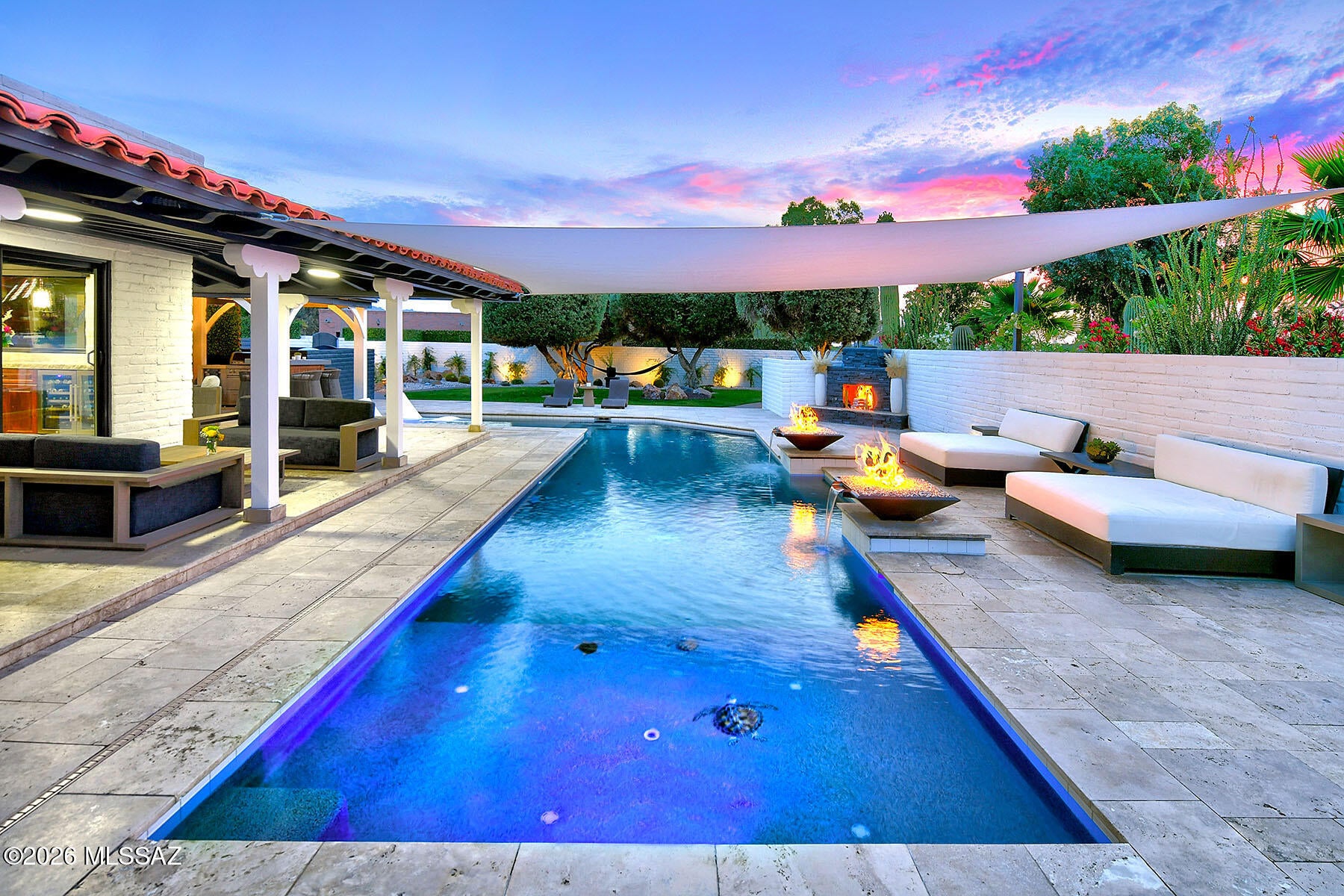 Stunning & elegantly remodeled contemporary territorial on the15th fairway of the prestigious Omni Tucson National Golf Club. Beautiful glass & iron front entry swivel door invites you into this exceptional home. Exquisite open concept Great Room with stacked stone fireplace, walls of sliding doors to give the indoor/outdoor atmosphere, 18'' Travertine tile floors throughout, oversized gourmet kitchen, knotty alder cabinets with a sensational 13-foot-long chiseled edge quartz countertop island, top-of-the-line stainless appliances, including a commercial grade gas range with 6 burners, griddle, & double ovens, dining area with dual-zoned wine cooler. 3 bedrooms, 3 full baths, including primary with a stacked stone floor-to-ceiling fireplace, luxurious bath with quartz countertops...... ....... double sinks, Jacuzzi tub, large double-headed shower with custom tile design. designer walk-in closet with built-in shelving & shoe racks. Fabulous backyard paradise which features a dramatic L- shaped, heated, saltwater Pebble-tec pool, 2 waterfalls & built-in firepots all covered with a custom 20' x 20' sunshade over the pool. Covered wrap-around patios, outdoor kitchen, grass play area, mature trees, mountain, golf course & sunset views. 3 car garage, small workshop area & circular paved driveway. Omni Tucson National Resort extends a membership discount to individuals who purchase property here.