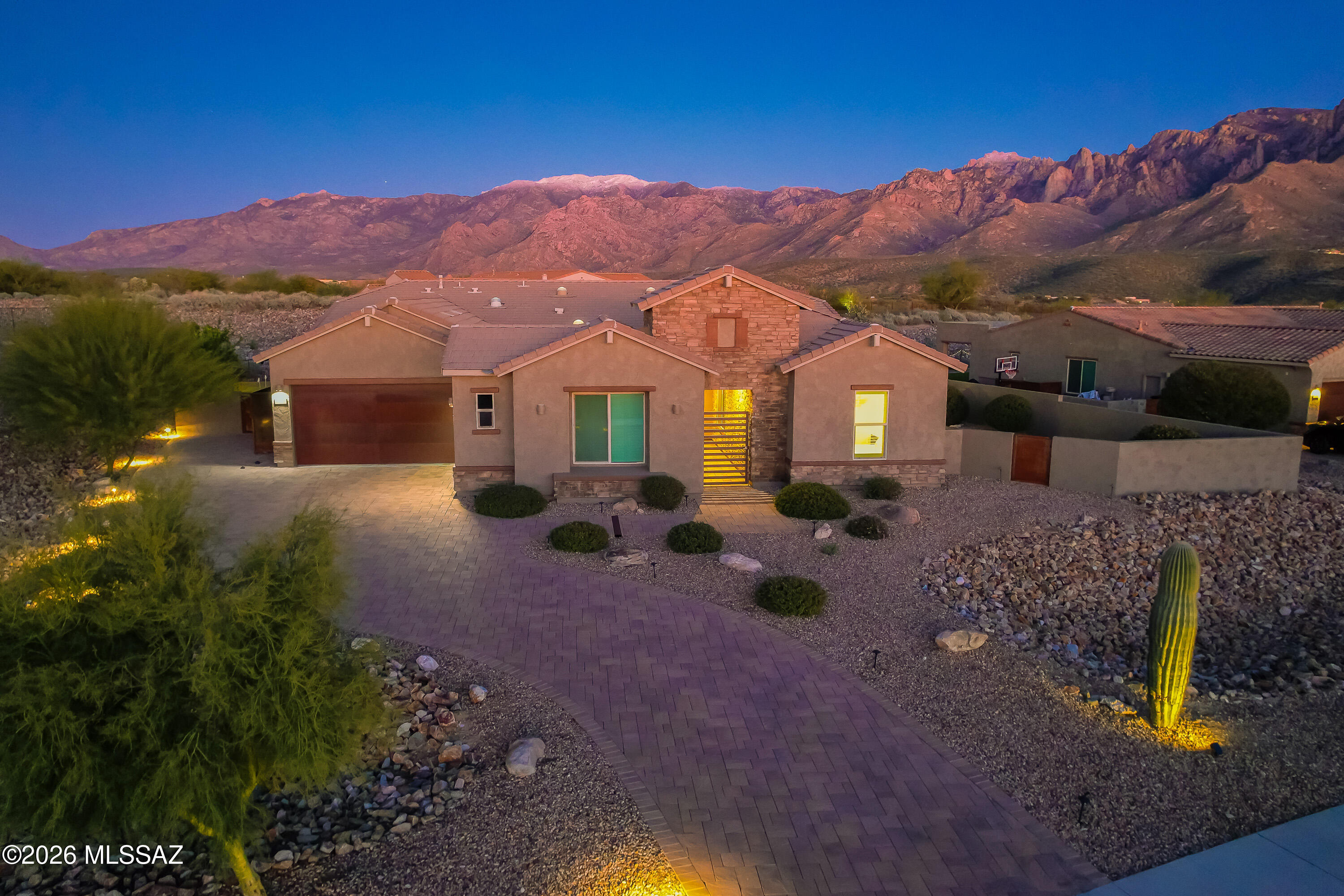Located in the gated Sanctuary at Silverhawke, this 3,269 square foot home offers 3 bedrooms and 3 full baths, all en suite, with a thoughtful, open layout and strong indoor/outdoor connection. Built in 2021 and recently refreshed, the home was repainted in December 2025 and features upgraded lighting, plumbing fixtures, and door hardware throughout the primary suite and guest wing. The kitchen is a focal point with quartz countertops, a large island, professional KitchenAid appliances, beverage refrigerator, built-in bar area, chandelier, reverse osmosis system, and an expanded layout created by removal of the original wall. Plantation shutters, solar tubes, and custom nine foot barn doors add architectural interest and natural light throughout. Outdoor living is equally well designed with a covered patio, motorized screen, misting system, built-in BBQ, low maintenance water feature with dedicated pool filter, putting green, and refreshed landscaping with new rock and saguaro additions. Additional features include a Tesla EV charger, whole home water softener, gas fireplace, freestanding primary soaking tub, primary closet pass through to the laundry room, and Pusch Ridge Mountain views. Conveniently located near shopping, dining, and everyday amenities, this home combines modern comfort, smart upgrades, and a lock and leave lifestyle in one of the area's most desirable gated communities.