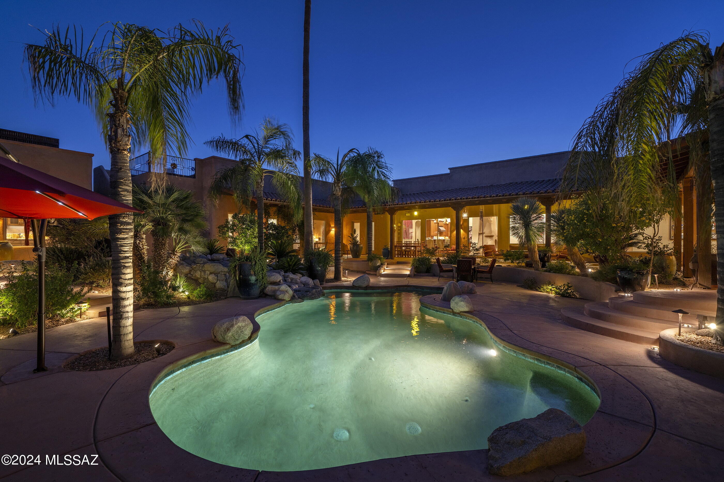 This one of a kind desert retreat, situated on 3.2 acres, is a study in thoughtful integration, defined by a regional vernacular that accents textures and the rich patina that echoes the hues of the surrounding desert landscapes. The property consists of 3 independent structures; a 4,123 sq ft Main House, 1,358 sq ft Guest House, and an additional 615 sq ft Guest House, with two garages incorporating five bays, all centered around a central courtyard that allows its owner to capture the dramatic desert light, while providing unobstructed views of the Catalina Mountains beyond. A private entry sequence, edged by lush native vegetation and shaded by mature mesquite trees, provides ample parking for guests without detracting from the understated elegance of the property. Low-profile landscaping subtly accentuates the architecture, guiding visitors toward the main entry in a seamless transition from public to private spaces. The interior features a carefully curated palette of materials that enhance a sense of place, with polished concrete floors, offering thermal massing that helps moderate the interior climate. Open sightlines from the interior frame the surrounding view corridors, while custom millwork adds warmth and texture to the space. The floor plan emphasizes a seamless flow between the living, dining, and outdoor rooms, creating a dynamic, yet cohesive living experience. The continuity of neutral and cohesive tones create a backdrop that allows the architecture and views to take center stage without overpowering the senses.

The kitchen is designed for both culinary precision and social gatherings, featuring warm wood finishes, paired with striking granite countertops and top-end appliances, maintaining continuity in the space. A generous central island with integrated Sharp drawer microwave yields additional workspace, while the layout ensures the kitchen remains open to the living and dining areas, making it ideal for both intimate and larger-scale entertaining. The primary suite is positioned to maximize privacy, with an en-suite spa-like bathroom and access to the private owner's courtyard, where vibrant native vegetation thrives alongside fragrant and prolific citrus trees.

In addition to the main house, the property includes two distinct guest house casitas, each thoughtfully designed to offer privacy and comfort, with their own exterior living spaces. The larger, 1,358-square-foot casita features a full kitchen, one bedroom, and one bathroom, ideal for long-term guests, or independent living. Its modern finishes, open-plan layout, and private patio provide a fully self-sufficient retreat. The 615-square-foot guest house also includes a full kitchen, integrated bedroom, and bathroom, designed with an open concept that maximizes space and natural light. Both casitas maintain the same high standards of design and materials as the main house, ensuring consistency throughout the property.

The outdoors are a true desert oasis, designed to evoke a resort-like atmosphere, with the pool acting as the centerpiece that mirrors the sky above and blends seamlessly into the surroundings. The central courtyard areas are framed by generous lounging patios, shaded by trees and deep covered overhangs, with a soothing water feature that meanders through the courtyard adding both a sensory and visual tranquility to the space. Each patio provides for sweeping views of either the Catalina Mountains, Pusch Ridge, or valley lights to the South, making this property the ideal location for year round relaxation.