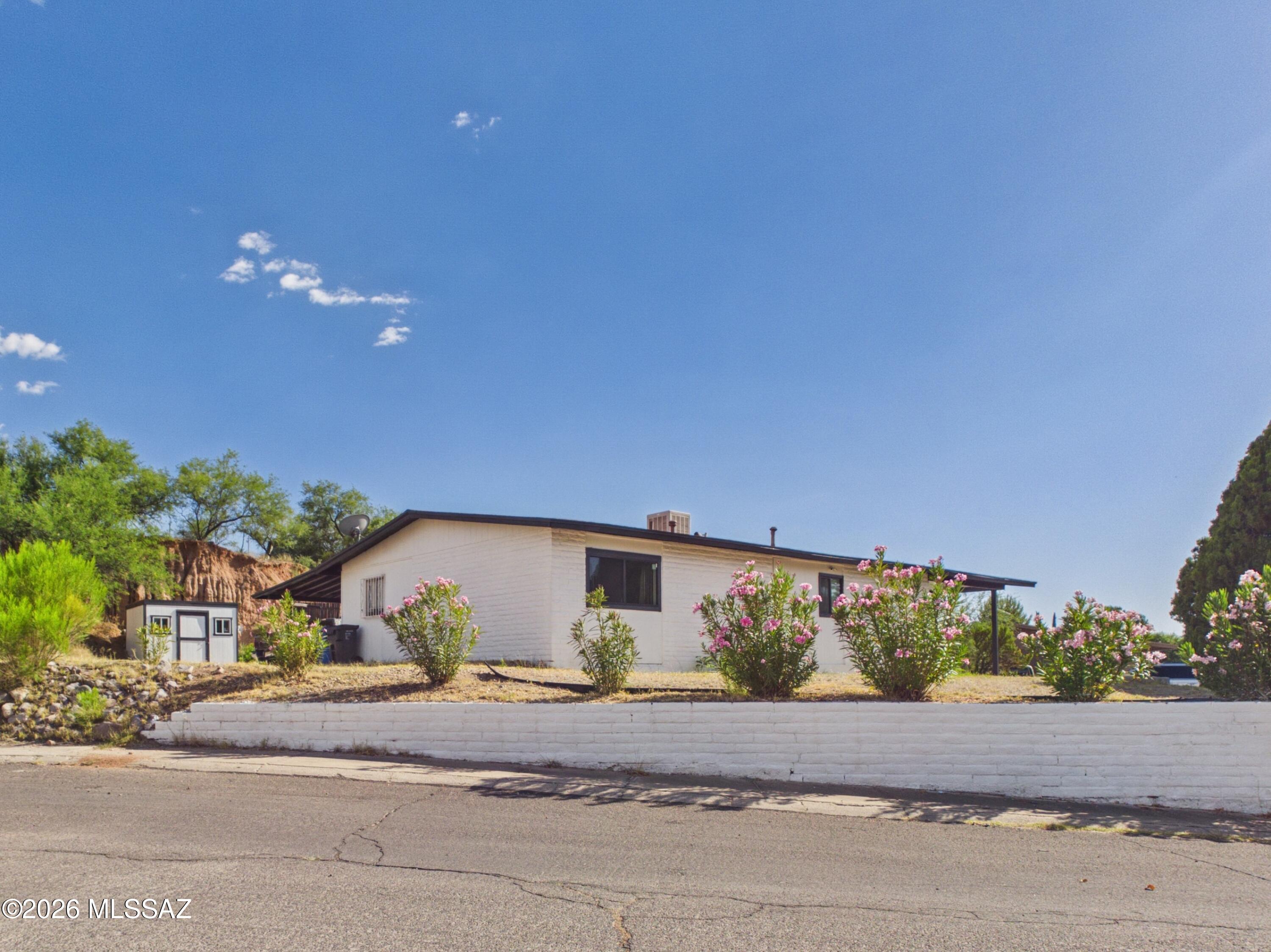 Thoughtfully maintained and full of character, this warm and welcoming 3-bedroom, 2-bath home offers comfortable single-level living on a spacious 0.27-acre lot in Nogales' Monte Carlo Estates. Freshly painted inside and out, the home features an open layout with wood-look flooring, painted brick accents, abundant natural light, and a generous breakfast bar that creates a natural gathering place between the kitchen and living areas. A versatile bonus room with a fireplace adds warmth and flexibility, making it ideal as a family room, game room, home office, hobby room, or den.

The kitchen offers ample cabinetry, stainless steel appliances, generous counter space, and a functional design that makes everyday living easy. Large sliding glass doors connect the living space to an expansive covered patio, creating a seamless indoor-outdoor flow ideal for relaxing, entertaining, or enjoying Nogales' beautiful weather.

The spacious backyard is framed by mature trees and offers plenty of room for gardening, outdoor recreation, pets, or future customization. A detached storage building provides added flexibility for hobbies, tools, or seasonal storage.

Conveniently located near Monte Carlo Trails, local schools, shopping, dining, and everyday conveniences, this property offers generous outdoor space, flexible living areas, and the comfort of a home that has been thoughtfully cared for over the years.