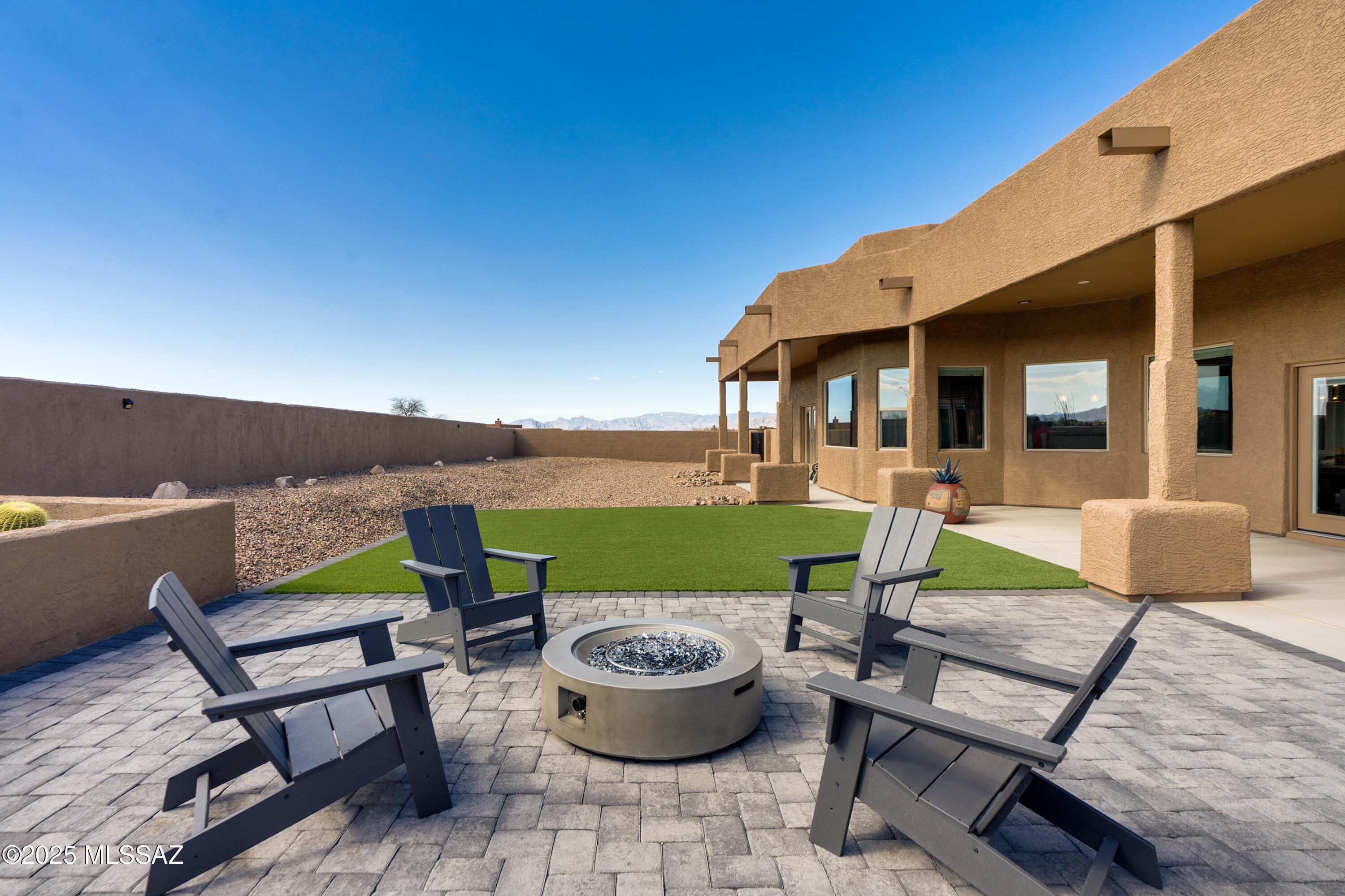 This masterfully maintained & tastefully upgraded suburban desert custom home is PRICED TO SELL w/a potential 2/1 BUY DOWN with an acceptable offer. Built in 2022, nestled in Mountain View Ranch at Windmill Ridge - with convenient access to the best of Vail's east side shopping, dining, entertainment, and recreation. Distinctive modern features include single-level open floor-plan with stained & scored concrete floors, abundant & expansive windows (framing picture-perfect views!), elevated ceilings, recessed lighting, wood-burning fireplace in Great Room, plus richly-appointed gourmet kitchen with premium stainless steel appliances, over-stove pot-filler, soft-close cabinetry, and high-grade granite countertops (which are matched in all bathrooms, as well). Spa-style Owners Suite showcases standing shower, double-vanity, walk-in closet, and provides private access to back patio. Two additional bedrooms, plus another full bathroom and one half-bath/powder-room, reinforce a perfect blend of preferential value & practical utility.

Expert-finished & walled outdoor areas enable breathtaking desert & mountain views. Morning sunrises greet the east-facing front courtyard, and evening sunsets can be enjoyed from the expansive, west-facing, resort-style backyard and covered patio.

Oversized & partitioned 3-car epoxy-floored garage provides spacious secure enclosed parking plus versatile storage optionality - while extended driveway offers ample additional on-site paved private parking.

Ideal for discerning individuals seeking luxury lifestyle in Greater Tucson Metro's Southeast Side, being in Vail also enables the property to enjoy night-sky/stargazing protections under the Pima County Outdoor Lighting Code (including prevention of unsightly lampposts & harsh bright lighting), plus the excellent reputation of the Vail Unified School District - consistently recognized as one of the best, top-performing districts in Arizona.

All in all, this dynamic property is ready to serve as a stellar starter for first-time homebuyers, an exciting change of space for seasoned homeowners, or even a potential income-producing asset for savvy investors.