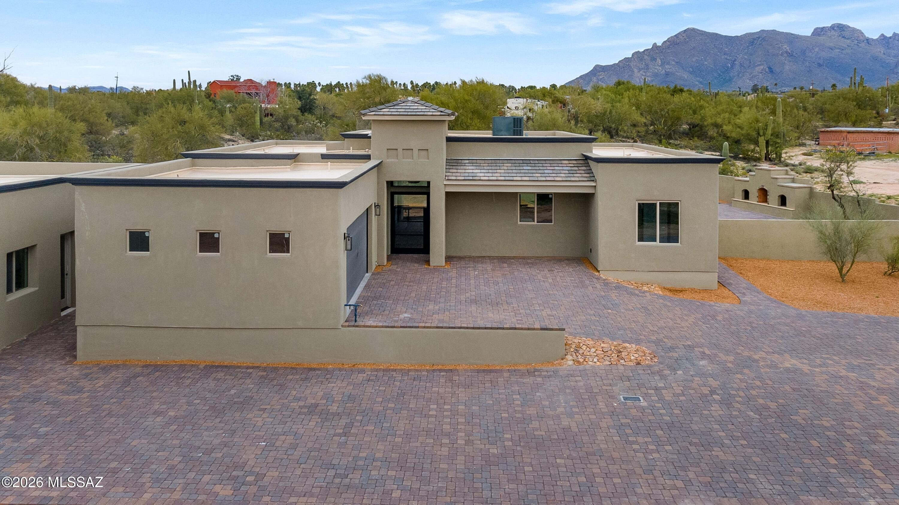 Luxury New Construction with Guest House & Catalina Views! Exceptional new custom home pn 1 acre with breathtaking Catalina & Pusch Ridge views located in exclusive gated community with NO HOA.The 2,250 sq ft main home features soaring ceilings, dyed and scored concrete floors, a designer kitchen with quartz countertops, custom cabinetry, and top-tier appliances. The spacious primary suite offers spa-quality finishes, custom vanities, and large walk-in closet. The standout feature is the stunning 984 sq ft guest house - complete with a full kitchen, living area, bedroom and bathroom. The versatile bonus room, with separate heating & cooling, is perfect for an office or gym. It is ideal for extended family, guests, or private rental income, offering its own 2-car garage and separate entrance for privacy & independence. Enjoy resort-style outdoor living with a large covered patio, built-in grill, outdoor fireplace, and a beautifully walled backyard. With 4 total bedrooms, 4 baths, and 4 garage spaces, this property delivers comfort, flexibility, and high-end craftsmanship in a spectacular setting.