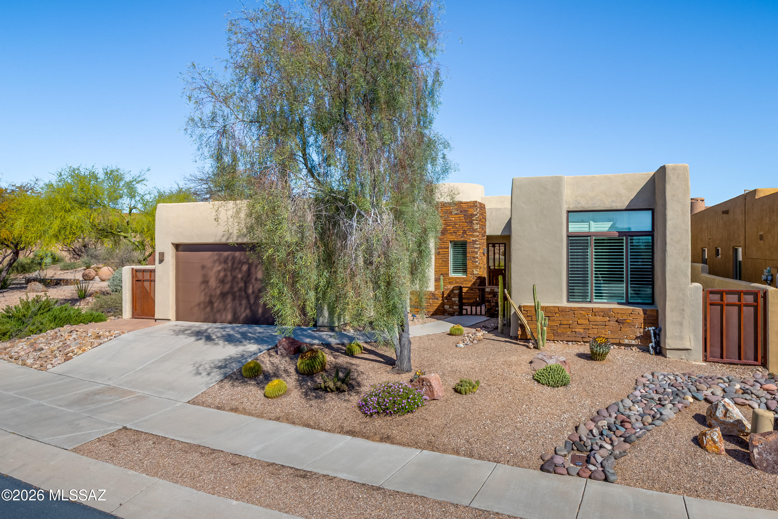 Tucked into the intimate Stone Village enclave at the entrance to Stone Canyon in Rancho Vistoso, this remarkable home designed by renowned architect Kevin Howard blends timeless architecture w/refined contemporary updates. With only 32 homes in the gated community, this home offers a rare combination of privacy, thoughtful design & proximity to the prestigious Golf Club at Stone Canyon. Beautifully reimagined 2,488sf home w/288sf detached casita w/its own private entrance ideal for guests, home office or multigenerational living. Light-filled open great room is anchored by a dramatic stacked-stone fireplace, soaring ceilings & distinctive curved architectural walls that define the home's signature style. Custom cabinetry, designer flooring, plantation shutters & carefully curated finishes create an elevated yet inviting & comfortable ambiance. Chef's kitchen was completely redesigned w/custom cabinetry, striking quartz counters, breakfast bar, induction cooktop, stainless appliances & custom beverage station featuring a 100+ bottle wine cooler, perfect for entertaining. Adjacent to the kitchen, a charming seating alcove w/circular ceiling & clerestory windows fills the space w/natural light & architectural character. Primary suite features a spa-inspired bath w/freestanding soaking tub, oversized walk-in shower, skylight & custom-designed closet. Additional bedrooms have been fully updated. Detached casita w/private entry & full bath provides an ideal space for guests, extended family, or a private office. Thoughtful upgrades extend throughout the property include all new flooring & paint, updated kitchen & baths, new Pella sliding doors, plantation shutters, designer lighting & whole-home water filtration system. Mechanical improvements include newer HVAC system while exterior enhancements include refreshed concrete finishes, rolling patio shades & complete landscape redesign w/artificial turf. But it doesn't end there, this community is adjacent to Oro Valley's Vistoso Trails Nature Preserve, featuring a 6.2-mile, eight-foot-wide concrete path that winds through the beauty of the Sonoran Desert and connects residents to some of Oro Valley's most scenic surroundings. Just minutes away, Honey Bee Canyon Park offers breathtaking hiking trails, dramatic rock formations, and protected desert landscapes that showcase the area's unique wildlife and natural beauty. Adjacent to Stone Canyon, you have options for golf and social memberships, opening the door to a world of exclusive privileges. A Golf Membership grants access to the championship golf course and health & fitness facility, along w/privileges at the clubhouse, dining facilities, locker rooms & participation in all club functions & activities. Sports Membership offers many of the same incredible benefits, excluding golf. Convenience meets lifestyle with Oro Valley Marketplace nearby, offering a variety of dining, shopping & entertainment options, including popular restaurants, retail stores & movie theater for an easy night out close to home. Seize this opportunity to live in luxury surrounded by pristine desert landscapes, endless outdoor recreation & the convenience of Oro Valley's best amenities.