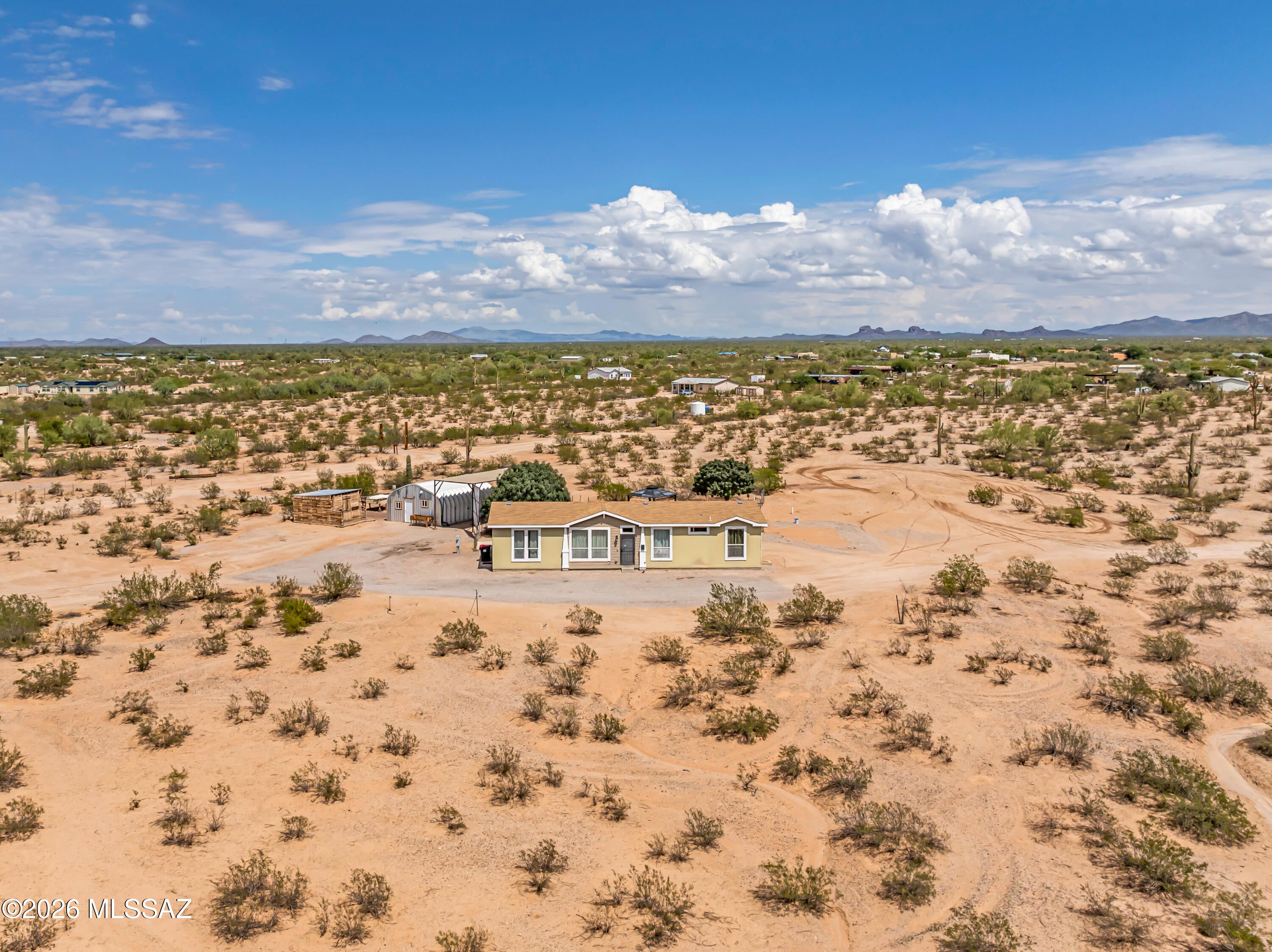 Enjoy wide-open Sonoran Desert living on 3.75 acres with panoramic views, beautiful sunsets, and no HOA. This spacious manufactured home offers plenty of room inside, plus versatile outdoor space for horses, RVs, ATVs, equipment, or future improvements. Additional features include a large trailer/RV shade structure and a separate partially finished metal outbuilding ideal for storage, a workshop, hobby space, or bunkhouse potential. Updated finishes include plank-style flooring and stainless steel appliances. Shared well serves five neighboring properties. Assumable VA loan at 4.375% may be available to qualified buyers.