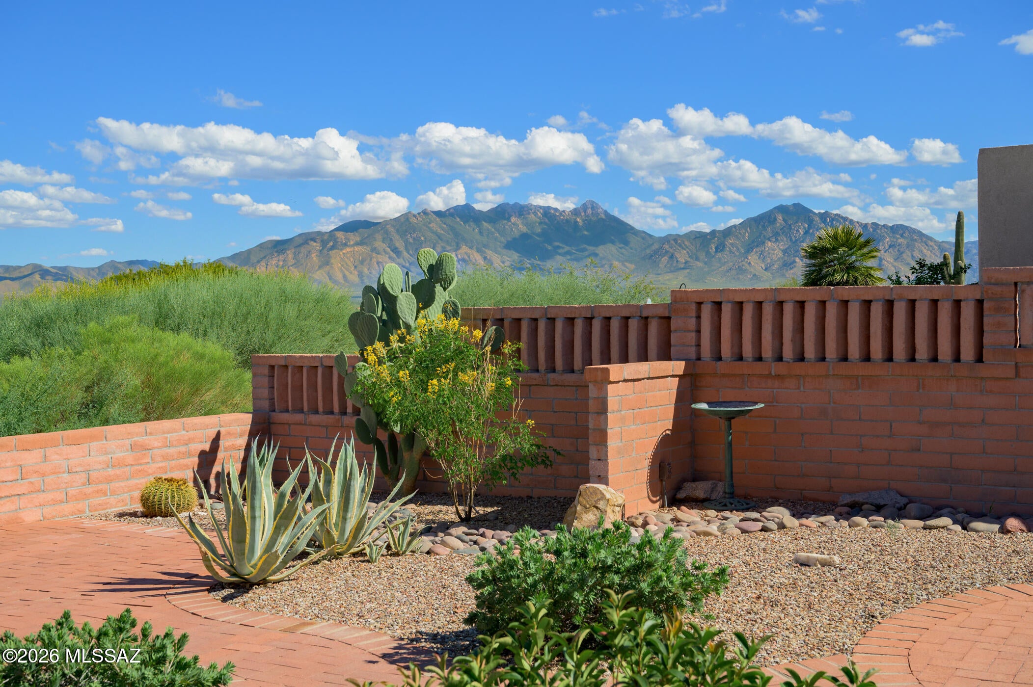 You will feel right at home in this townhouse designed for the active retiree seeking comfort, convenience, and spectacular mountain views. Step inside to discover rich, Southwest-inspired tile flooring that flows gracefully throughout the main living areas. Impressive 12-foot ceilings, clerestory windows, and strategically placed skylights fill the home with natural light, establishing a warm, inviting atmosphere. The efficient U-shaped kitchen features stainless-steel appliances and a dining nook with captivating views of the surrounding desert landscape and mountains, ideal for casual dining. An arched opening above the kitchen sink connects the kitchen and living area, facilitating conversation and social interaction with family and guests.  The primary suite is notably spacious, with an extension that can serve multiple purposes, such as a cozy sitting area, hobby room, exercise space, or office. The guest bedroom and bath are thoughtfully located in a separate wing to ensure privacy. Step outside to your east-facing patio where unobstructed views of the Santa Rita Mountains await. Mornings begin with breathtaking sunrises, while evenings offer a chance to unwind as vibrant desert sunsets cast unique colors across the sky.  Nestled in a gated community, residents benefit from exclusive access to the pool just down the street, along with membership to Green Valley Recreation's exceptional amenities. This is an ideal Southern Arizona home for those seeking a special winter getaway or an active, vibrant retirement lifestyle.