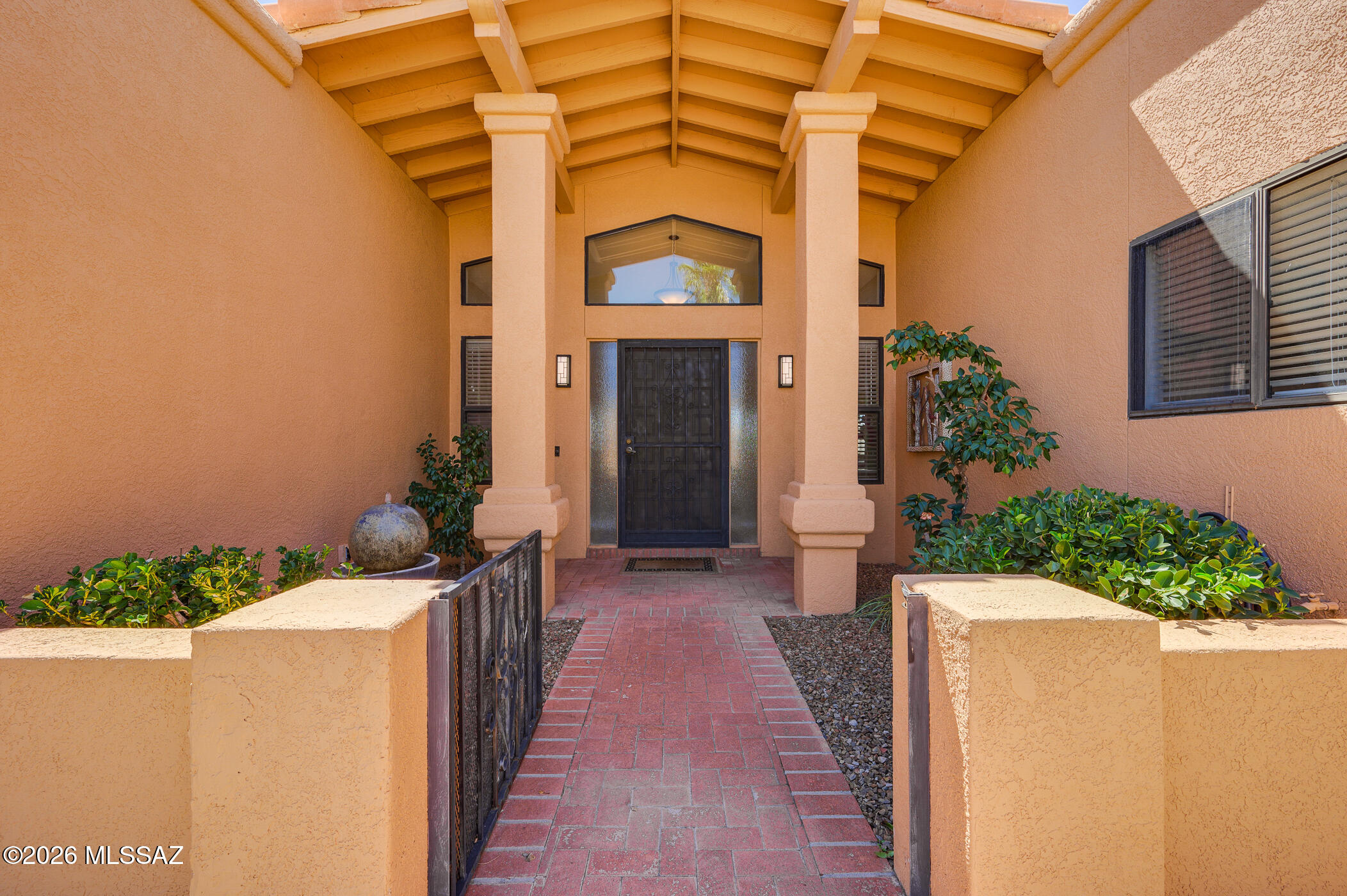 An attractive, gated front yard leads to a dramatic interior. Step into a spectacular great room featuring a beamed 14ft vaulted ceiling and abundant clerestory windows. Look beyond to a wrap-around patio and pleasant mountain views. Tiled floors throughout and arched gateways lead to a stunning, new kitchen of white cabinetry, quartz counters, stainless steel appliances, an island and walk-in pantry. Split bedrooms provide excellent privacy. The large primary suite contains a separate office and access to the rear patio. The magnificent great room, the architectural intricacy of niches and arches and the clever combination of a tile and built-up roof distinguish this custom home. As a bonus it is being sold fully furnished.