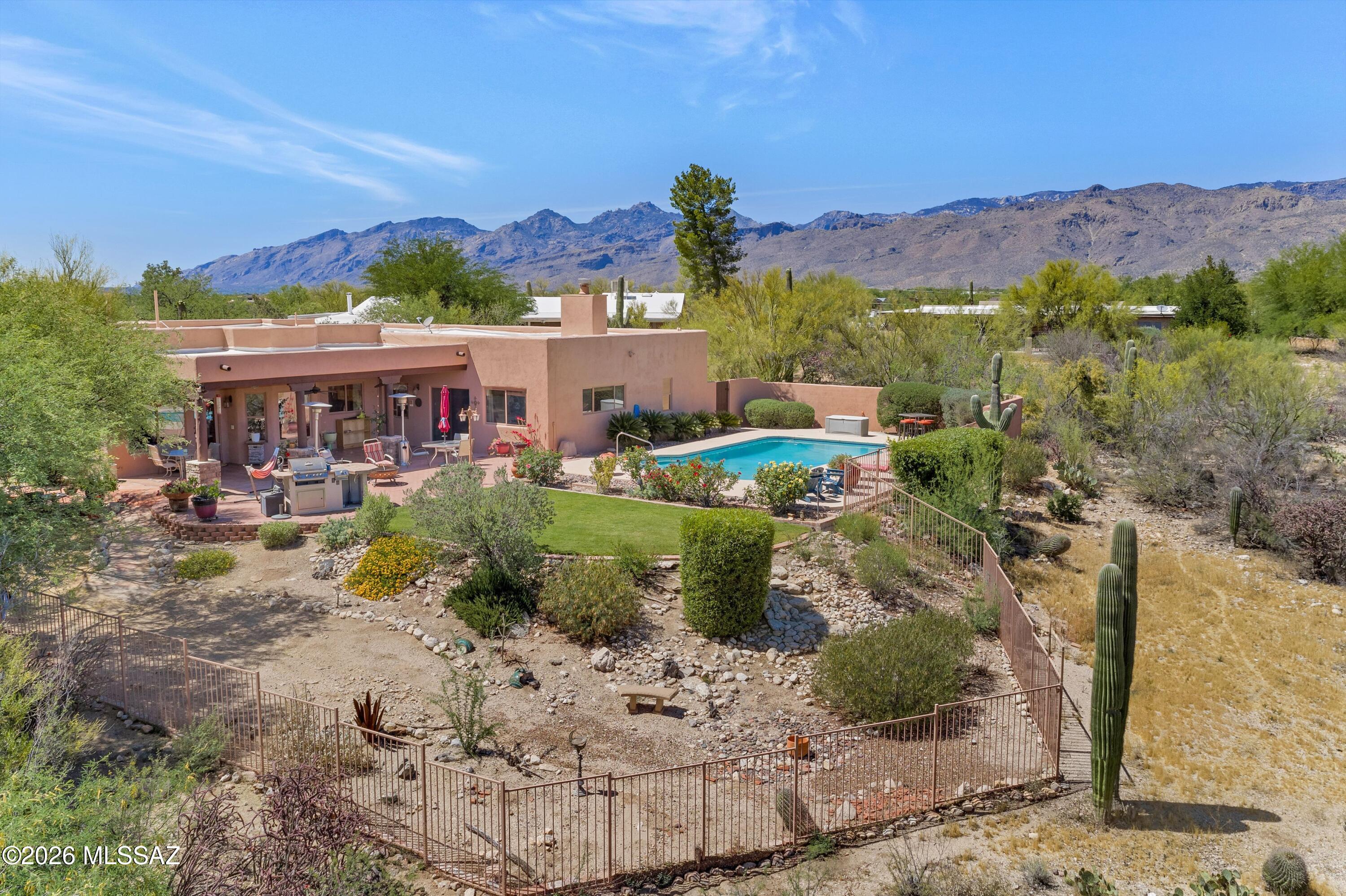 Stunning SW style home has been lovingly updated and polished to perfection. Gracious 4 BR/ 2.5 BA welcoming design that includes living & dining room near entry and then an open concept kitchen and family room with soaring viga beam ceilings. Kitchen has been redesigned with expanded island granite counters abundant natural wood cabinetry & SS appliances.  Bay window nook and picture windows frame the Rincon mts. Gracious primary suite boasts dual sided fireplace, jetted tub and walk in shower. Delightful backyard is a desert oasis with solar heated pool, crisp grass, roses, mature landscaping, tile covered patio and gas BBQ. Oversized 3 car garage plus storage/ workshop w/ evaporative cooler. An elevated cul-de-sac setting on over an acre, with sweeping views ideal for outdoor enjoyment. Nestled in the vibrant Tanque Verde Valley, this home is just minutes from golf, local restaurants, schools and everyday shopping. Enjoy the convenience of nearby access to Tucson's outdoor recreation, including parks, hiking trails, and scenic desert landscapes.