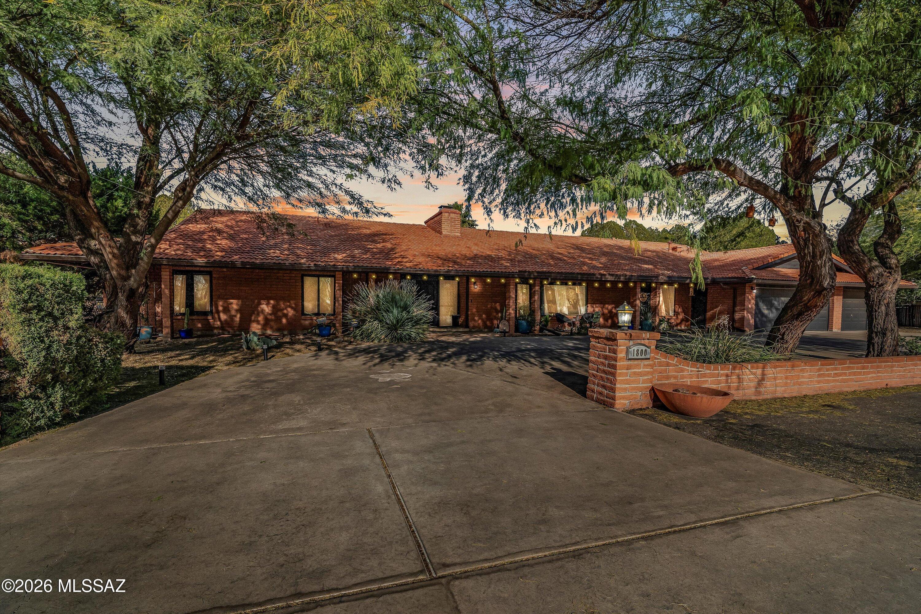 Exceptional estate-style living on the 8th fairway of Forty Niners Country Club in the highly sought-after Tanque Verde Valley. This rare 4,127 sq ft single-story home offers 4 bedrooms, 4 full bathrooms, and a true split floor plan with dual primary suites—ideal for multigenerational living or guests. Expansive living areas anchored by a fireplace and walls of glass overlook the golf course. Nearly 2,000 sq ft of covered patios, a pool with slide, mature landscaping, and a 3-car garage on a .59-acre lot complete this exceptional property. Designed for both comfortable daily living and large-scale entertaining, this expansive single-story estate offers a layout, scale, and outdoor living experience that is increasingly rare to find. The property combines privacy, generous interior space, and exceptional outdoor areas in a setting framed by mature desert landscape with a backdrop of mountain views.
Inside, the home offers open and inviting living spaces designed for both everyday living and entertaining, with natural light and sightlines that connect the main living and dining areas. The thoughtfully designed split floor plan includes four bedrooms and four full bathrooms, including dual primary suites that provide flexibility for multigenerational living, extended guests, or private workspaces.
Each bathroom is spacious and well appointed, featuring wood-look porcelain tile flooring, updated vanities, modern lighting, and thoughtfully selected tilework, including subway tile surrounds and decorative geometric accents that add character and a refined, contemporary feel. The primary bathroom stands out with its expansive layout, dual vanities, large mirrors, a separate soaking tub and tiled walk-in shower, and the kind of space and storage rarely found in homes of this era.
The kitchen is both striking and highly functional, designed to serve as a true gathering space rather than just a work area. Quartz countertops provide extensive prep and serving space, complemented by abundant cabinetry, stainless steel appliances, and a modern tile backsplash that adds texture and visual interest. The scale of the kitchen allows multiple people to cook and prep comfortably at the same time something buyers immediately notice when touring the home. Open sightlines connect the kitchen to the surrounding living and dining areas, creating a natural flow between cooking, dining, and everyday living.
The expansive living areas are anchored by a fireplace and framed by large sliding glass doors that bring in natural light and open directly to the covered patios. The indoor-outdoor connection is seamless, creating a sense of openness and space that makes the home feel even larger than its already impressive square footage. The thoughtful layout offers flexibility for formal entertaining and casual gathering areas allowing the home to adapt easily to a variety of lifestyles.
One of the most remarkable features of this home is the nearly 2,000 square feet of covered patio space, creating an outdoor living environment that truly functions as an extension of the home. Multiple seating areas, ceiling fans, shaded dining spaces, and wide open views provide the perfect setting for entertaining year-round.
The backyard is both private and inviting, featuring a sparkling pool with slide, mature landscaping, and sweeping views across the golf course. The combination of shade, open space, and greenery creates a setting that feels peaceful, private, and ideal for both quiet evenings and large gatherings.
The expansive .59-acre lot provides additional flexibility, space between neighbors, and the kind of breathing room that is increasingly difficult to find.
Additional highlights include a dedicated laundry room with cabinetry, counter space, and a utility sink, generously sized secondary bedrooms, extensive storage throughout, and a separate storage room with its own sink, ample counter space, and built-in storage ideal for crafts, hobbies, or working on projects. A three-car garage and mature landscaping with established trees further enhance the sense of privacy and create a beautifully established setting.
Located in the Tanque Verde Valley, the home offers easy access to hiking, riding trails, and outdoor recreation, while still being convenient to shopping, dining, and everyday amenities. The property is also located within the highly regarded Tanque Verde school district.
Properties offering this combination of single-story living, estate-level square footage, golf course frontage, and expansive outdoor entertaining space are rare. This home offers the scale, flexibility, and setting to accommodate everything from quiet evenings to large gatherings making it a truly special opportunity.