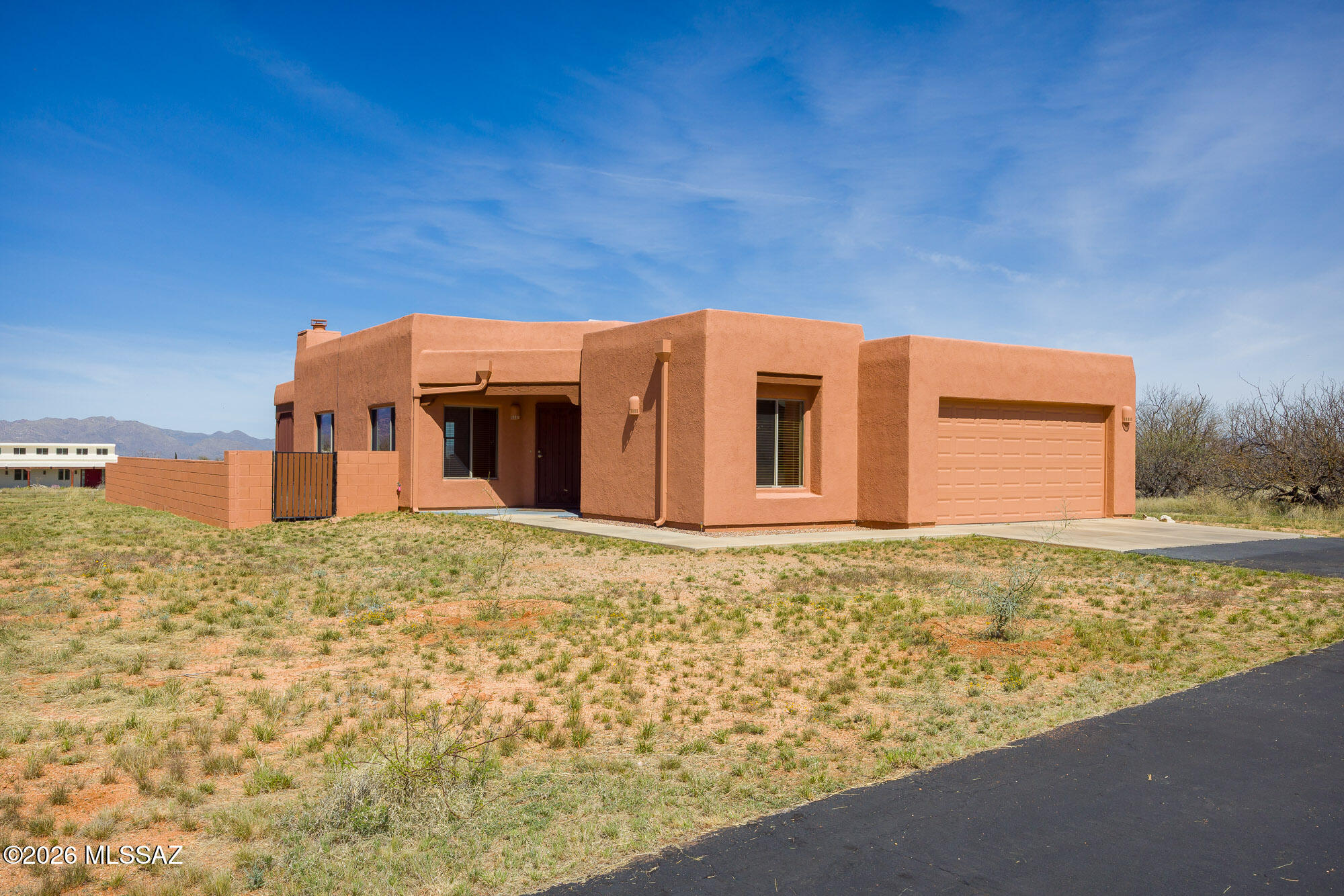 Experience the ultimate desert serenity with this stunning 3-acre property in the prestigious Red Hawk at J-6 Ranch. Situated at an elevation of 4,345 feet, you'll enjoy noticeably cooler summers and unparalleled stargazing under pristine night skies. This 1,809-square-foot ranch home features a thoughtful open-concept floor plan, highlighted by a cozy corner fireplace and rustic wood beams that create a warm, lodge-like ambiance. The interior offers 3 spacious bedrooms and 2 full bathrooms, while custom wrought-iron doors provide both security and style. Step outside to a walled backyard that overlooks a scenic grove of mesquite trees, perfect for quiet reflection or entertaining. Combining country privacy with modern comfort, this is a rare opportunity for peaceful living in Benson.